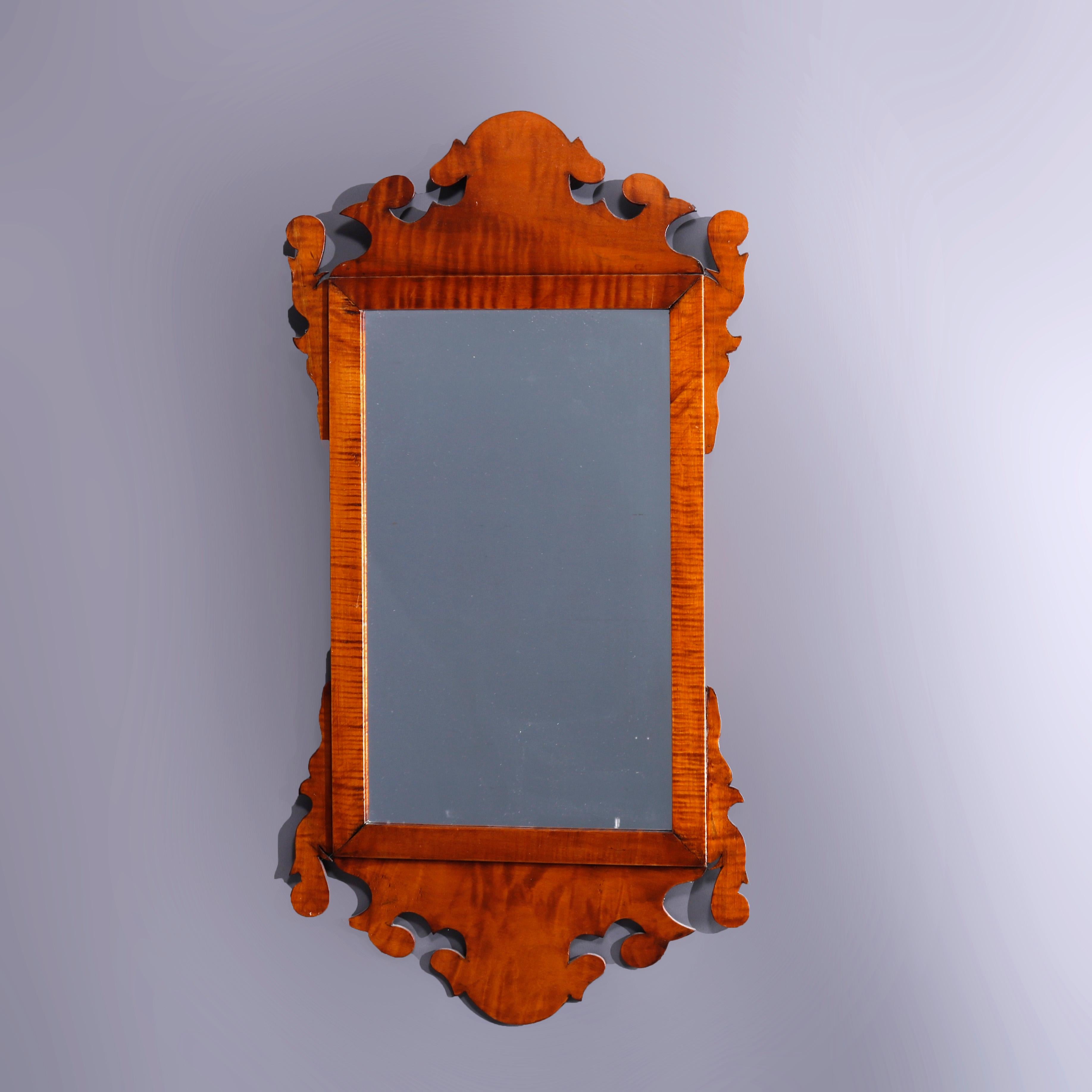 A Federal style wall mirror offers tiger maple construction shaped with scroll and stylized foliate elements, 20th century

Measures - 34.25'' H x 17.5'' W x 1'' D.