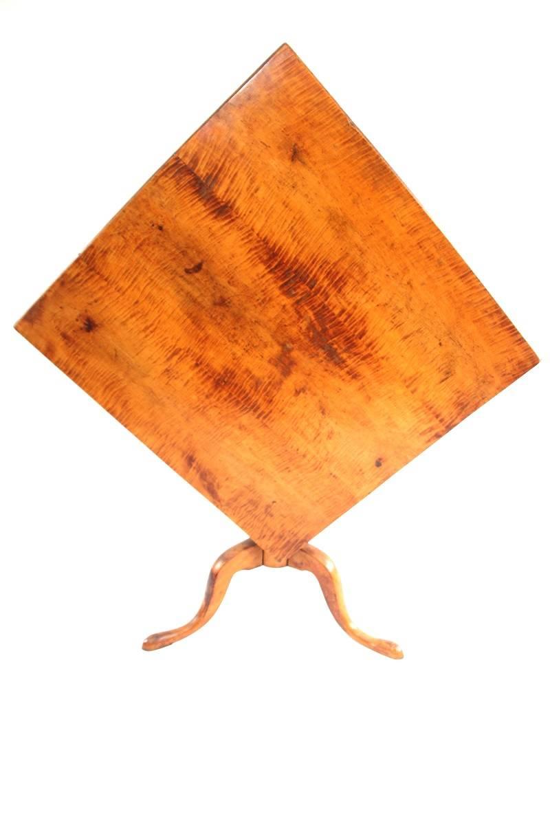 Federal tiger maple tilt-top tea table with square three-board top hinged and joined above the maple urn-turned standard raised on tripod cabriole leg base terminating in pad feet. 
 
New England, early 19th century
 
Measures: 27.75 inches H x