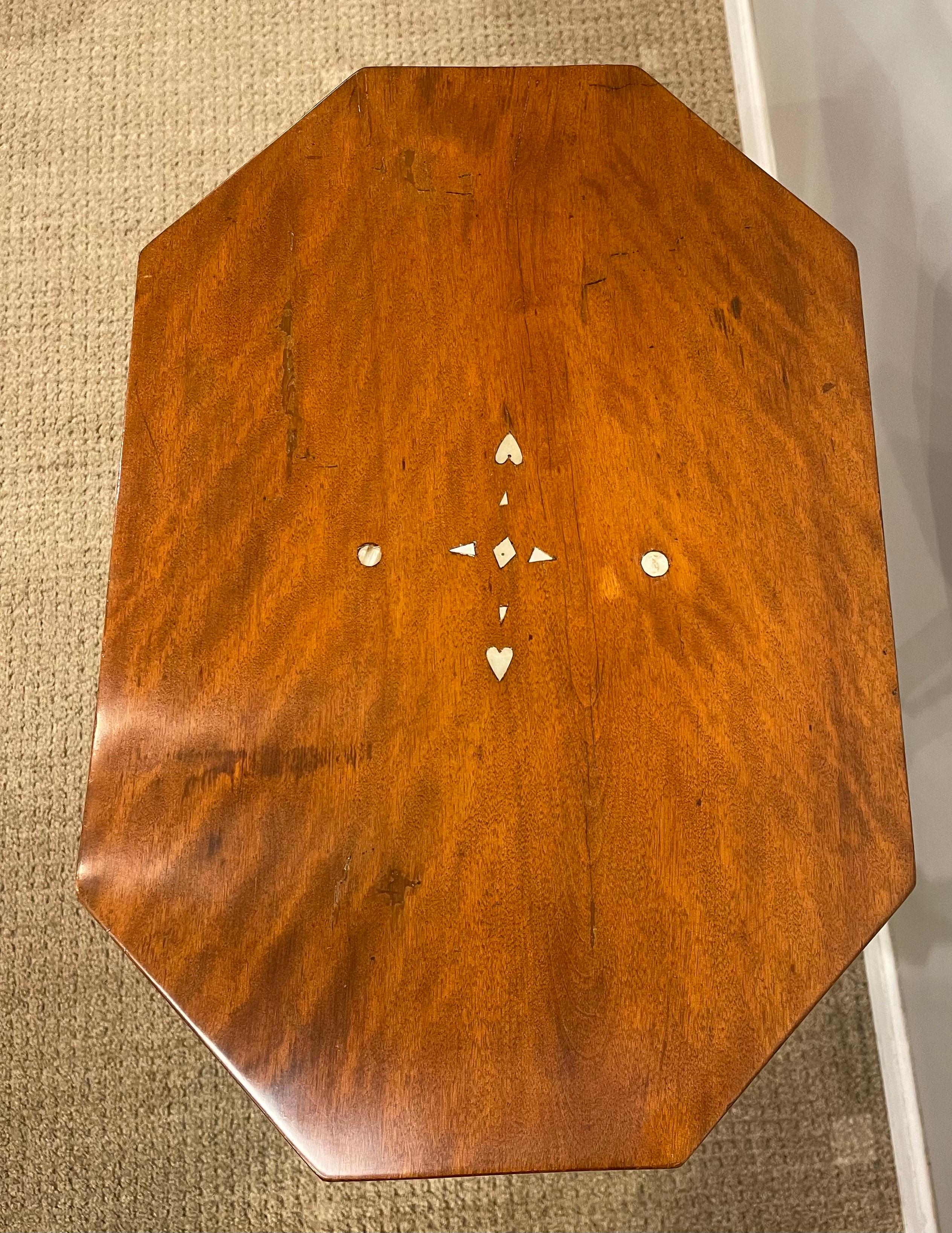 Table tripode en érable tigré, plateau aux angles chanfreinés également incrusté de nacre, de cercles, de cœurs et de triangles. Les pieds sont tournés et reposent sur des pieds balancés vers le bas qui se terminent par des pieds bêche.