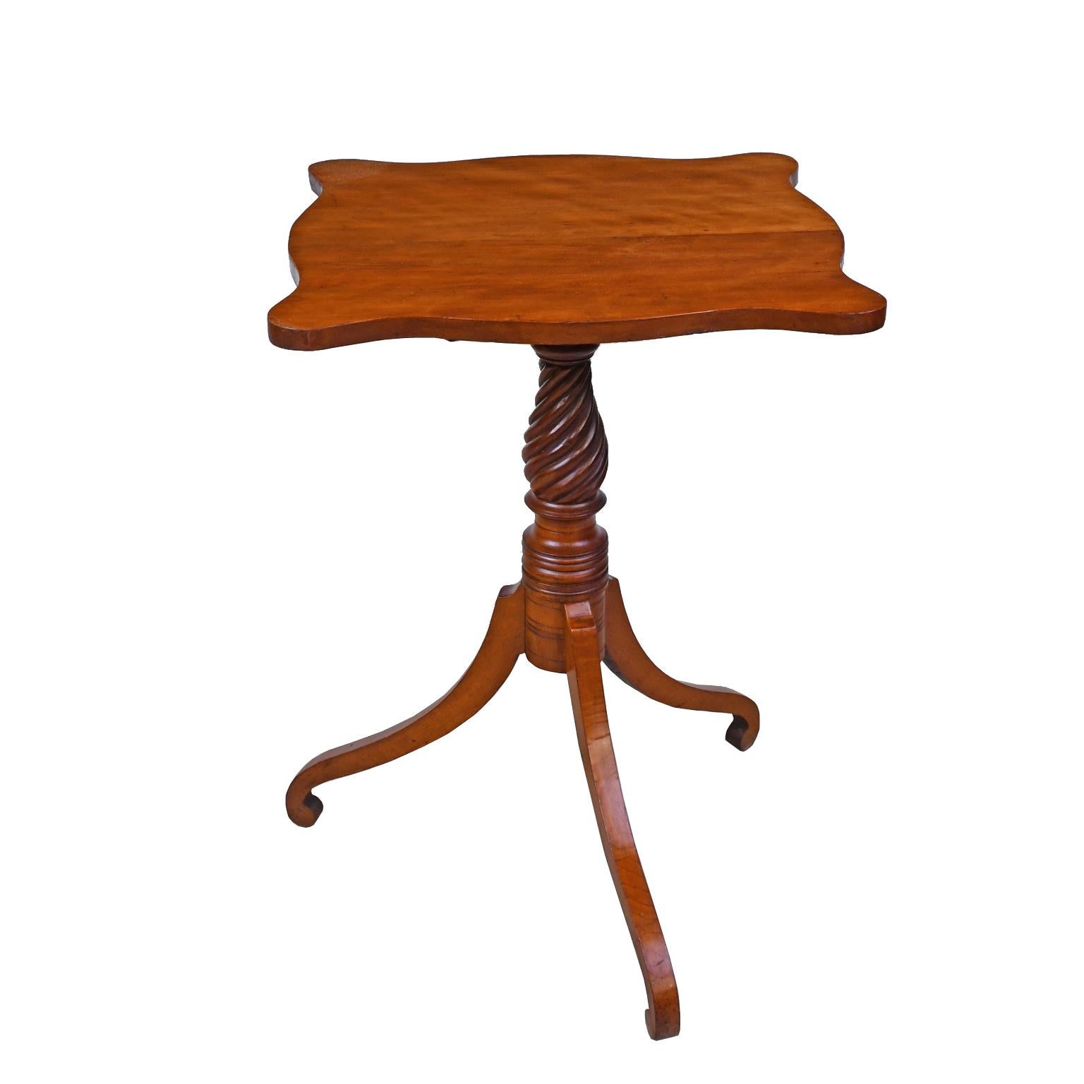 A lovely Federal tilt-top table in cherrywood with tripod base that historically doubled as a candlestand. The candlestick could rest on the ledge provided when the tabletop was tilted up and not in use. The curved top is on a pedestal with a