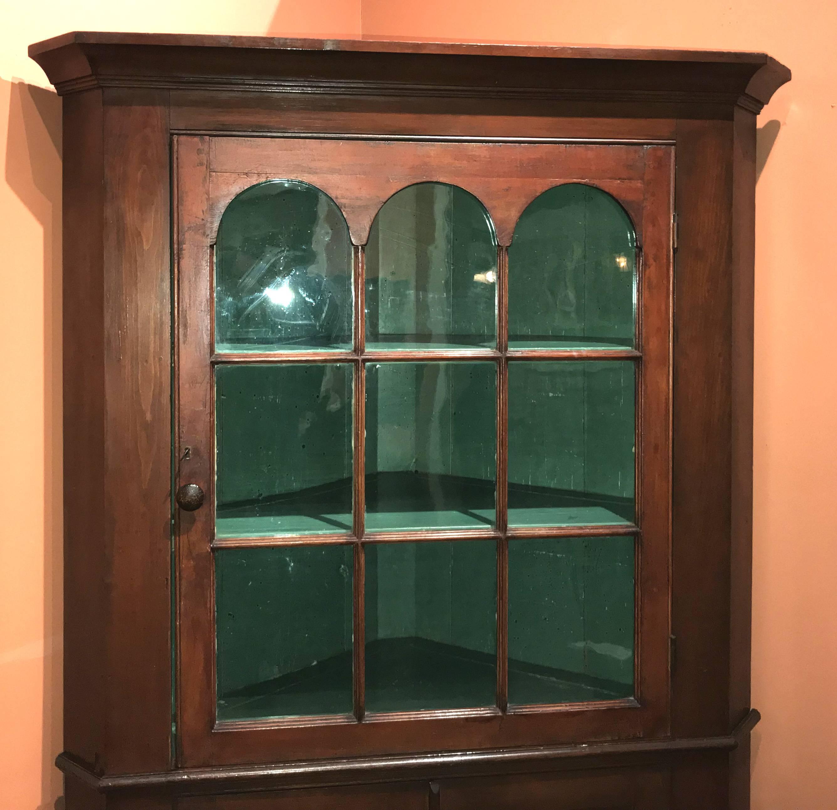 A fine Federal period two part cherry cupboard, its upper case with molded cornice surmounting a glazed triple arch glass door with wavy glass panes, opening to reveal a green painted interior with two interior shelves, over a lower case with waist