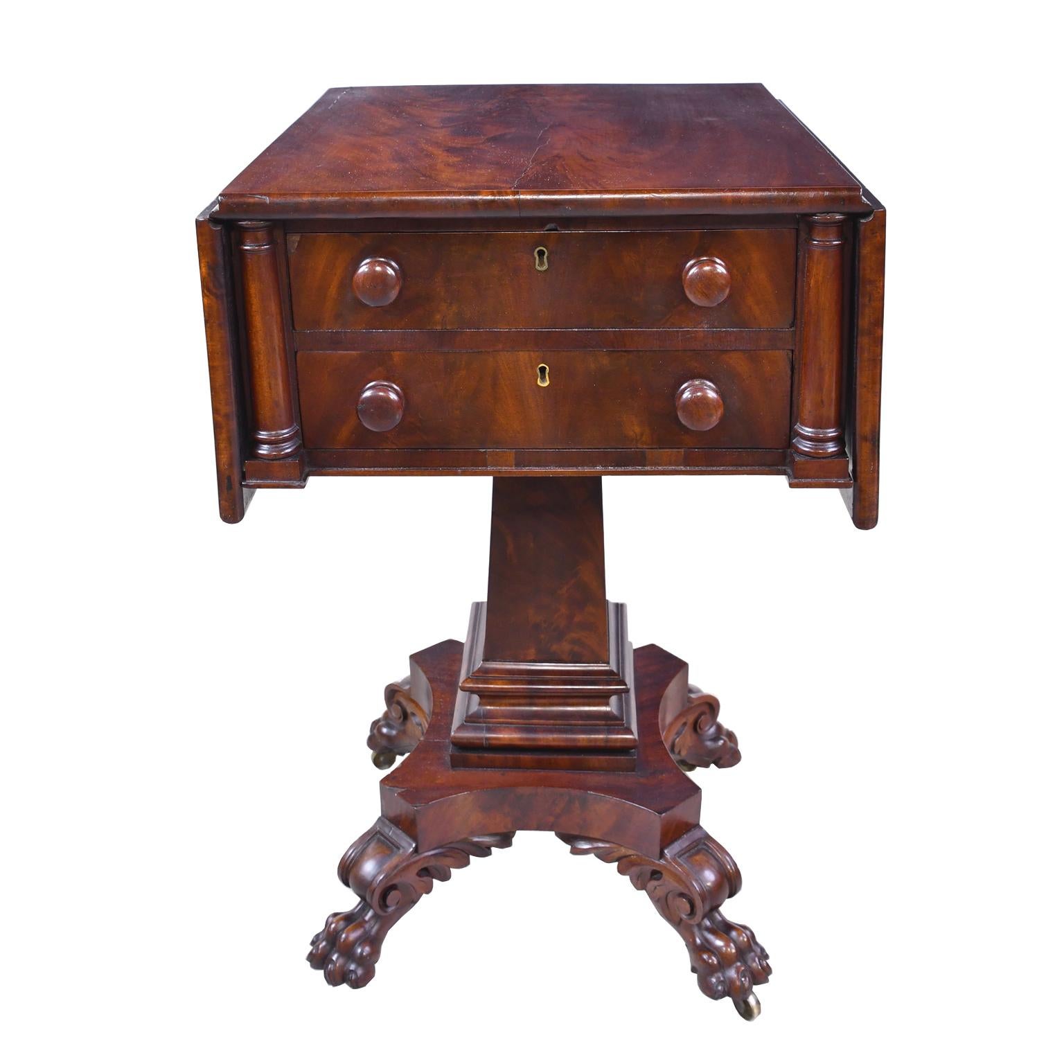 A very handsome Federal work table in fine West Indies mahogany with fold-down leaves. There are two drawers with two rounded columns flanking each side. Drawers have the original turned pulls. Top rests on a square column that gradually widens