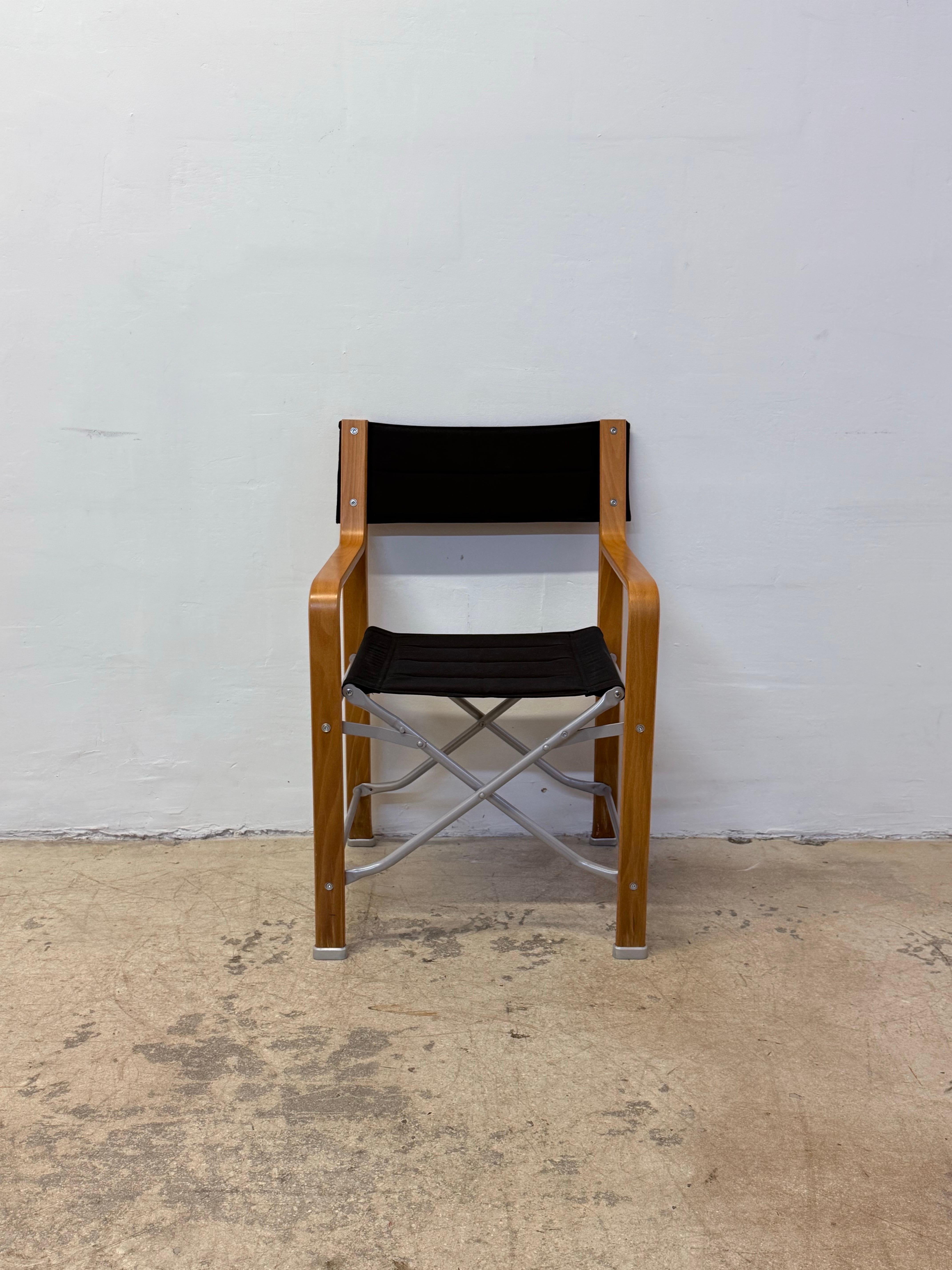 Silla de director plegable con armazón de madera curvada y acero con asiento y respaldo de lona negra, de Federico Giner.