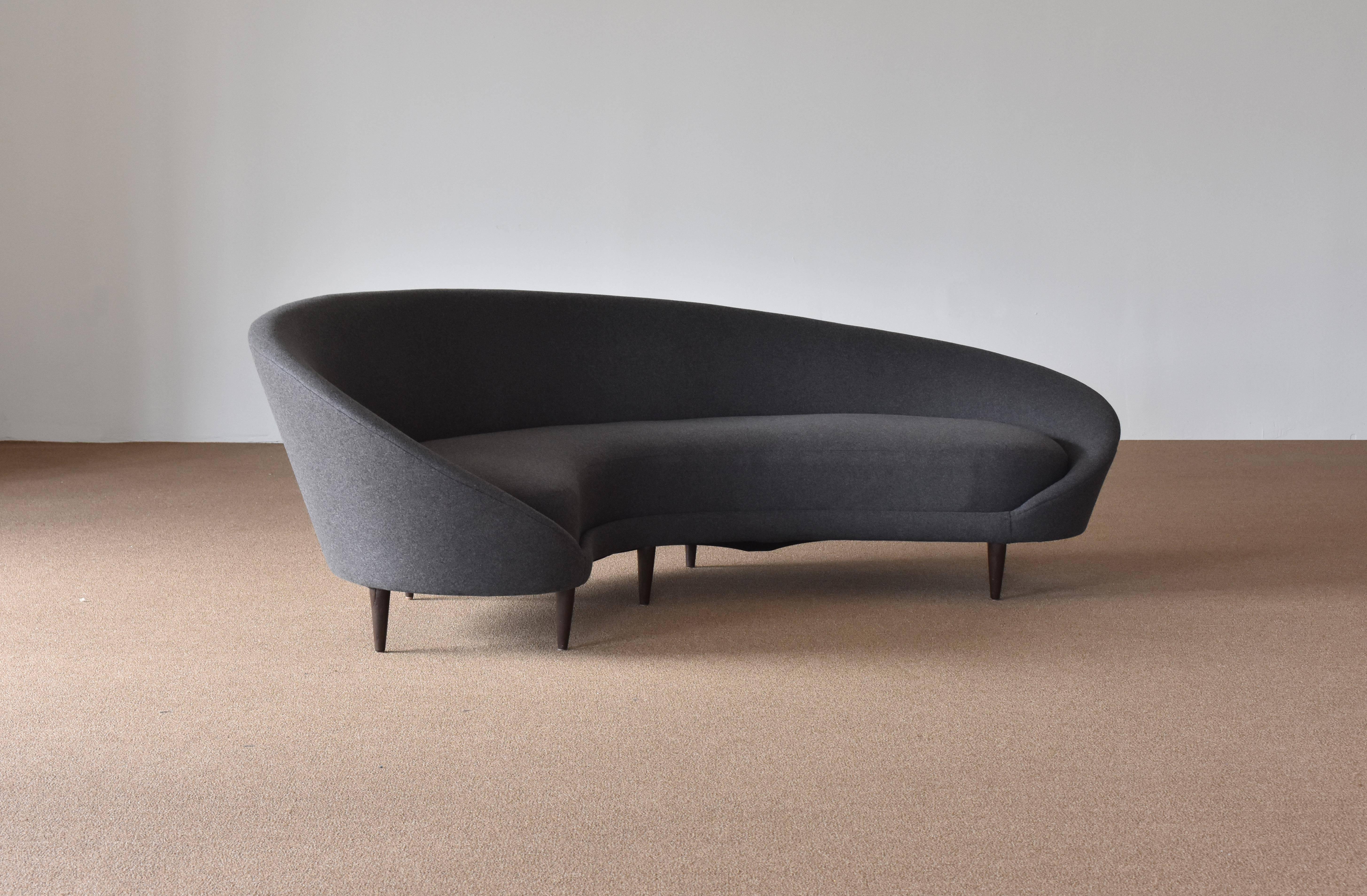 A curved / organic sofa by Federico Munari. Upholstered in a brand new medium dark grey wool fabric. Stained oak legs. The present sofa is an authentic example of this design from the 1950s sourced directly from Italy. Pre-restoration images