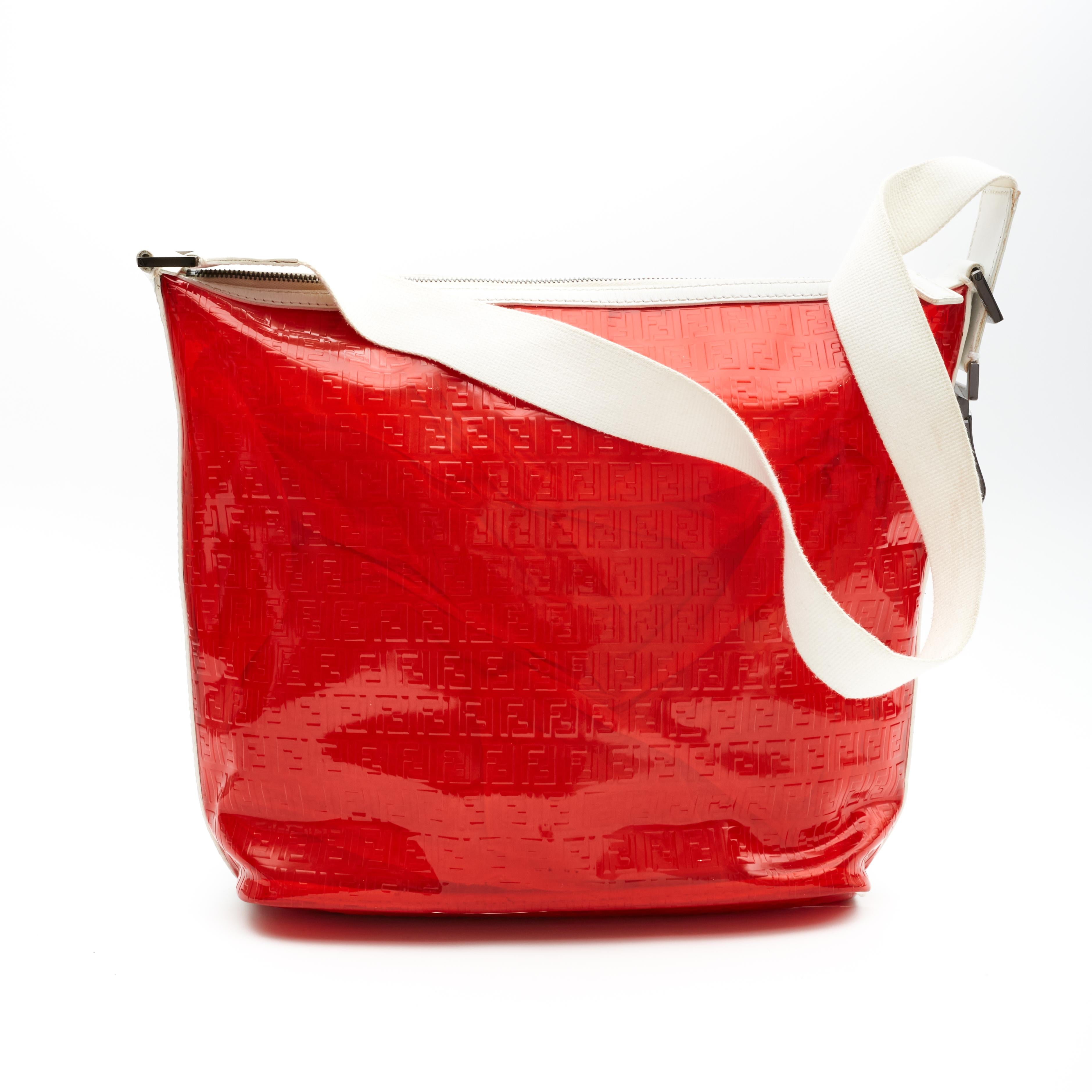 This large Fendi shoulder bag is made with transparent red PVC plastic with white leather finishes. The bag features the zucca monogram embossing throughout, a large white leather shoulder strap, top zip closure and an open