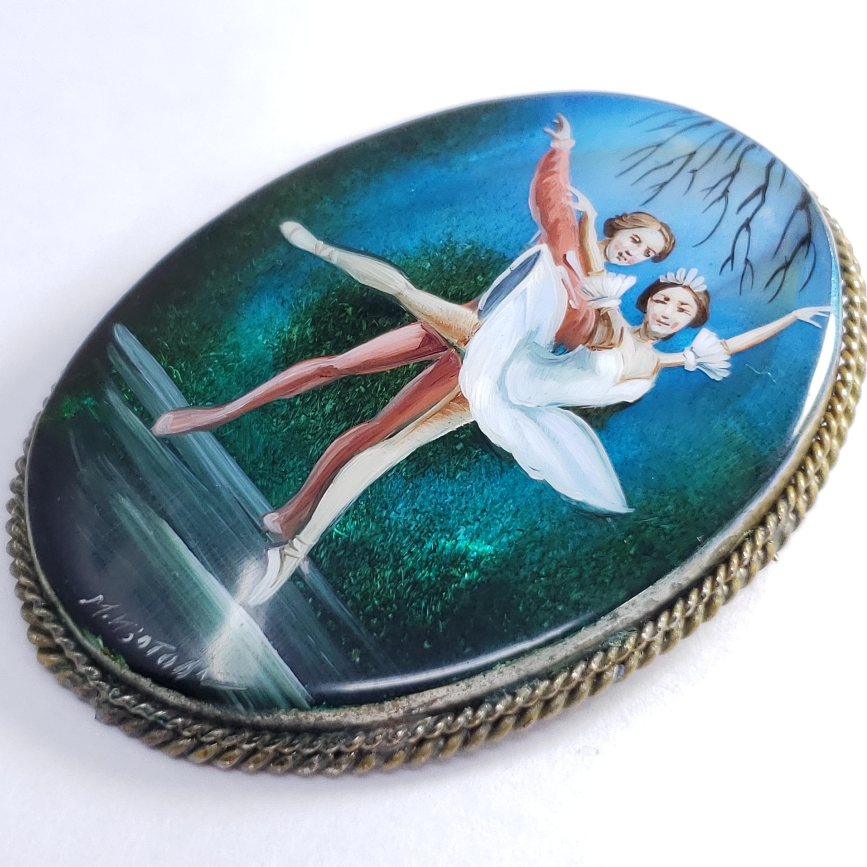 Exquisito broche ruso Fedoskino engastado en un bello bisel de plata alemana. Presenta una pareja de bailarinas de ballet sobre un fondo azul verdoso, pintado a mano sobre una piedra de nácar con una capa de laca.

Firmado por el artista - M Izotova