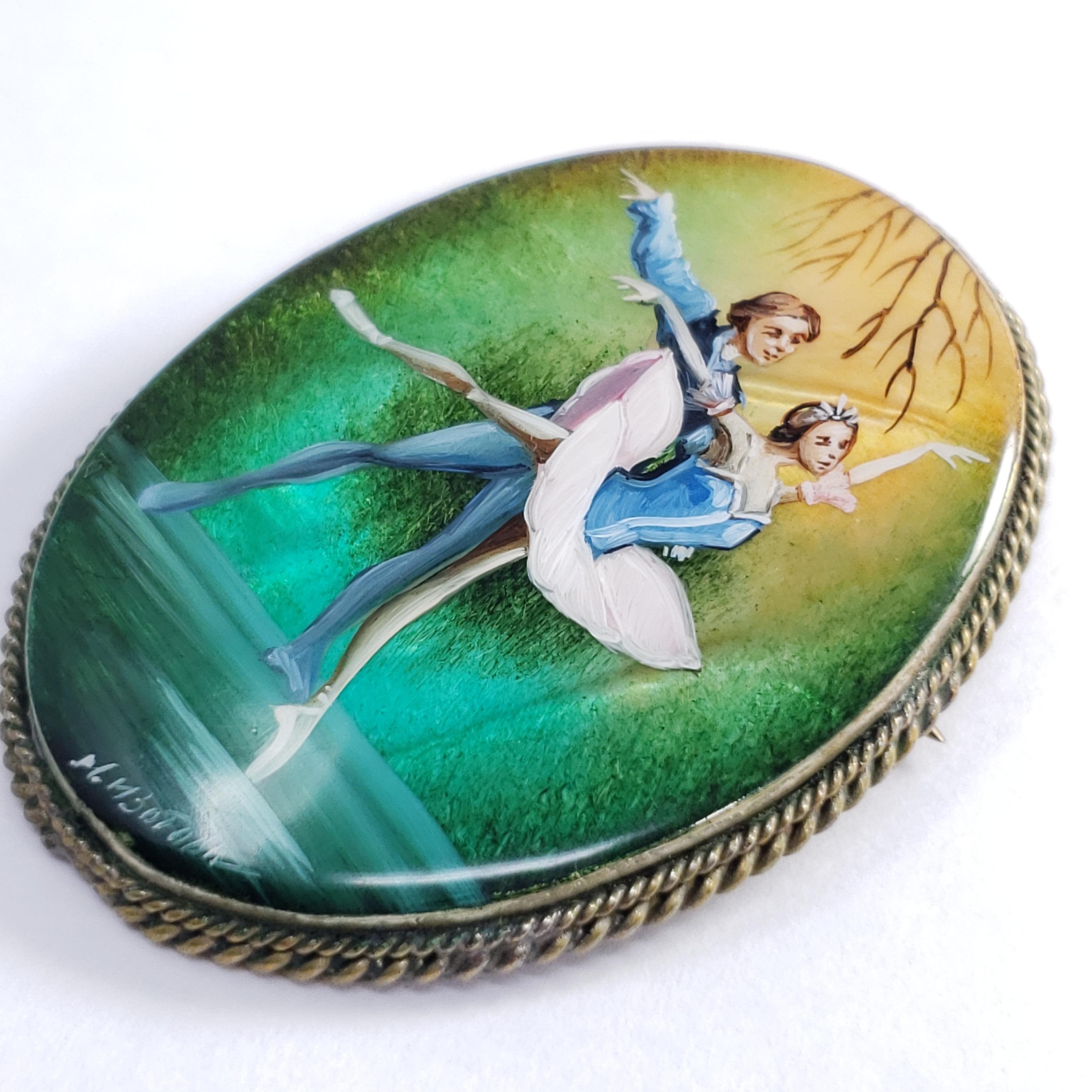 An exquisite Russian Fedoskino brooch set in a beautiful German silver bezel. Features pair of ballet dancers on a green and yellow background, hand-painted on a mother-of-pearl stone with a layer of lacquer.

Signed by artist - M Izotova (М