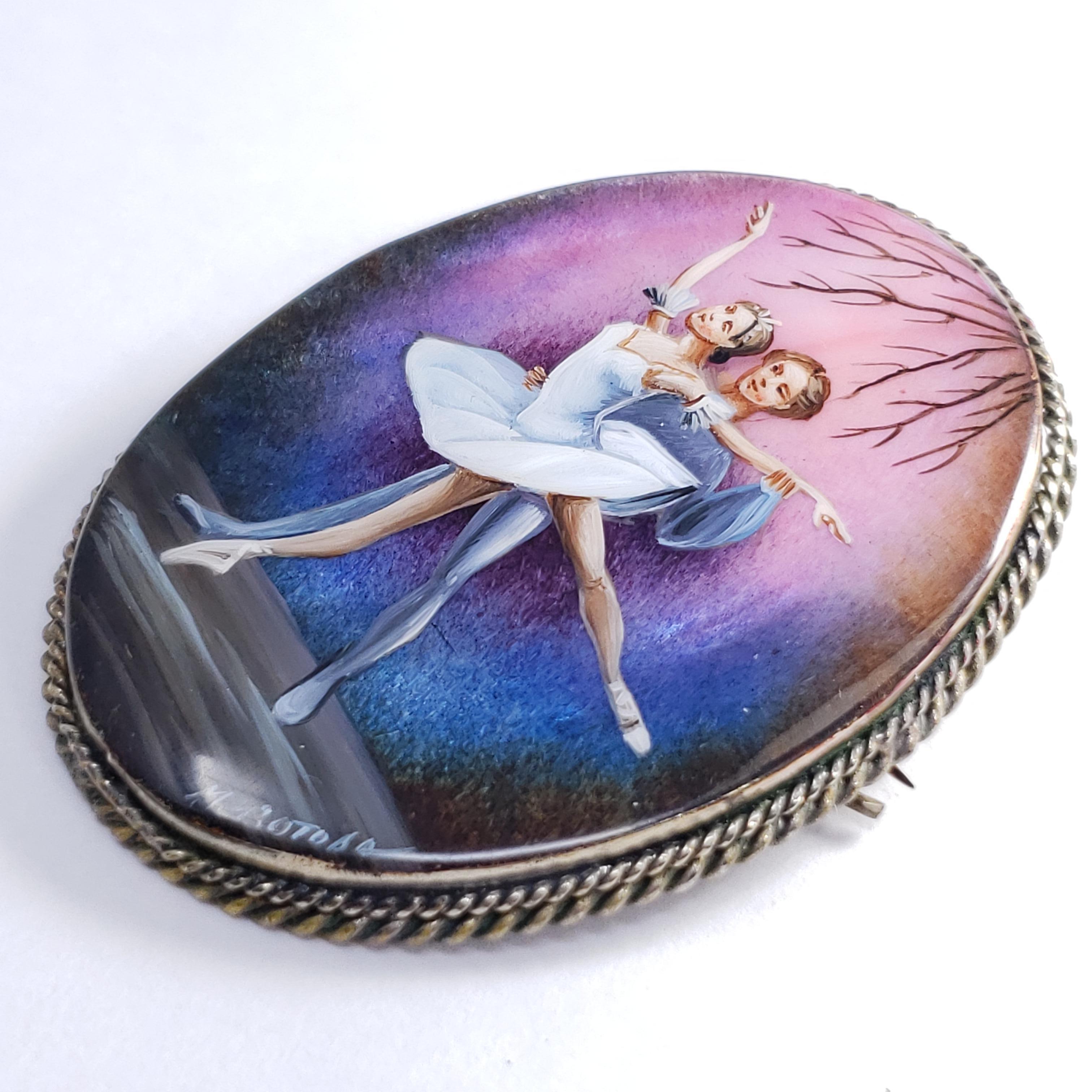 An exquisite Russian Fedoskino brooch set in a beautiful German silver bezel. Features a pair of ballet dancers on a blue & violet background, hand-painted on a mother-of-pearl stone with a layer of lacquer.

Signed by artist - M Izotova (М