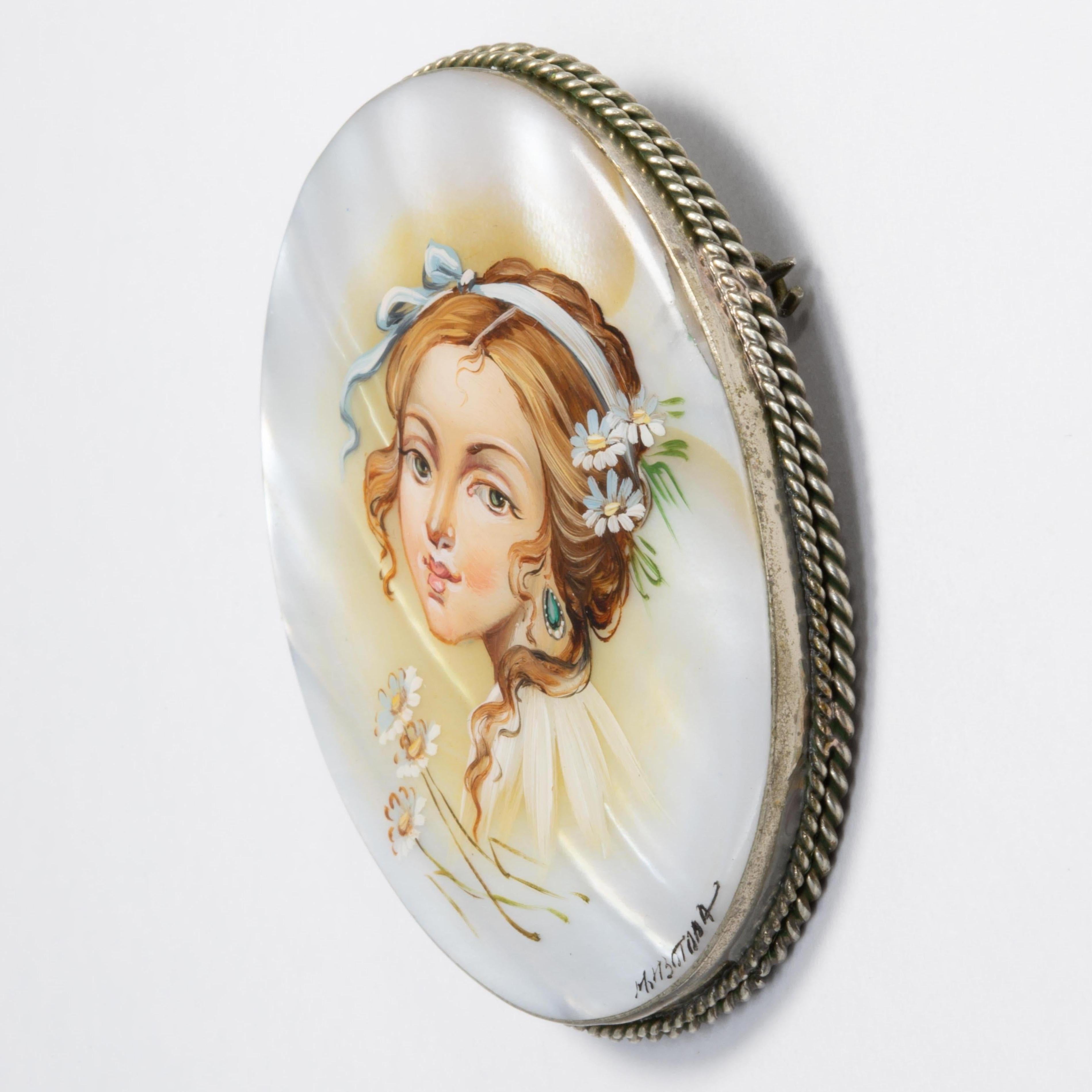 An exquisite Russian Fedoskino brooch set in a beautiful German silver bezel. Features a likeness of a beautiful woman, hand-painted on a mother-of-pearl stone with a layer of lacquer.

Signed by artist - M Izotova (М Изотова)

Circa early 1900s