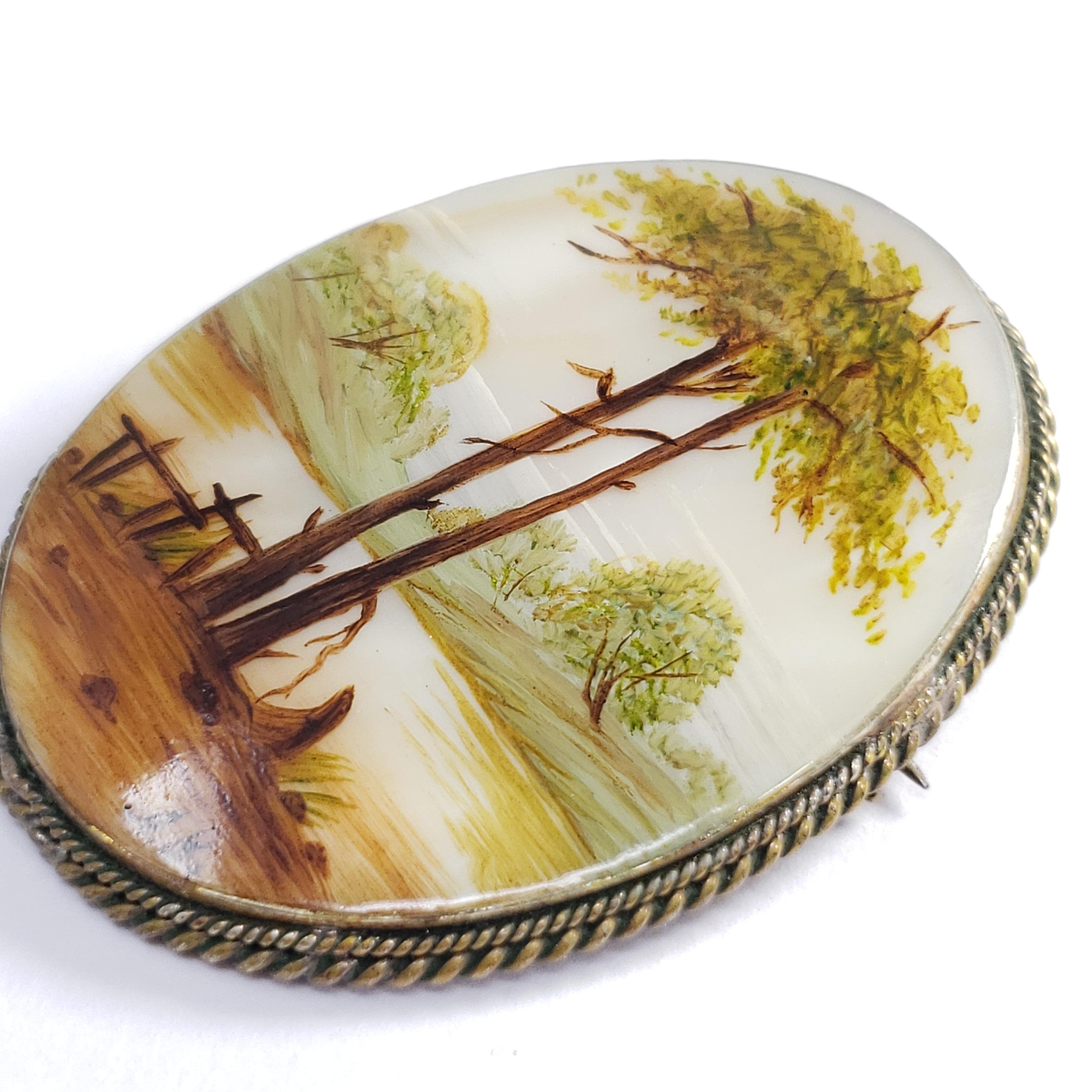 An exquisite Russian Fedoskino brooch set in a beautiful German silver bezel. Features a rustic landscape with two trees in warm earth tones, hand-painted on a mother-of-pearl stone with a layer of lacquer.

Signed by artist - L.B. (Л. Во)

Circa