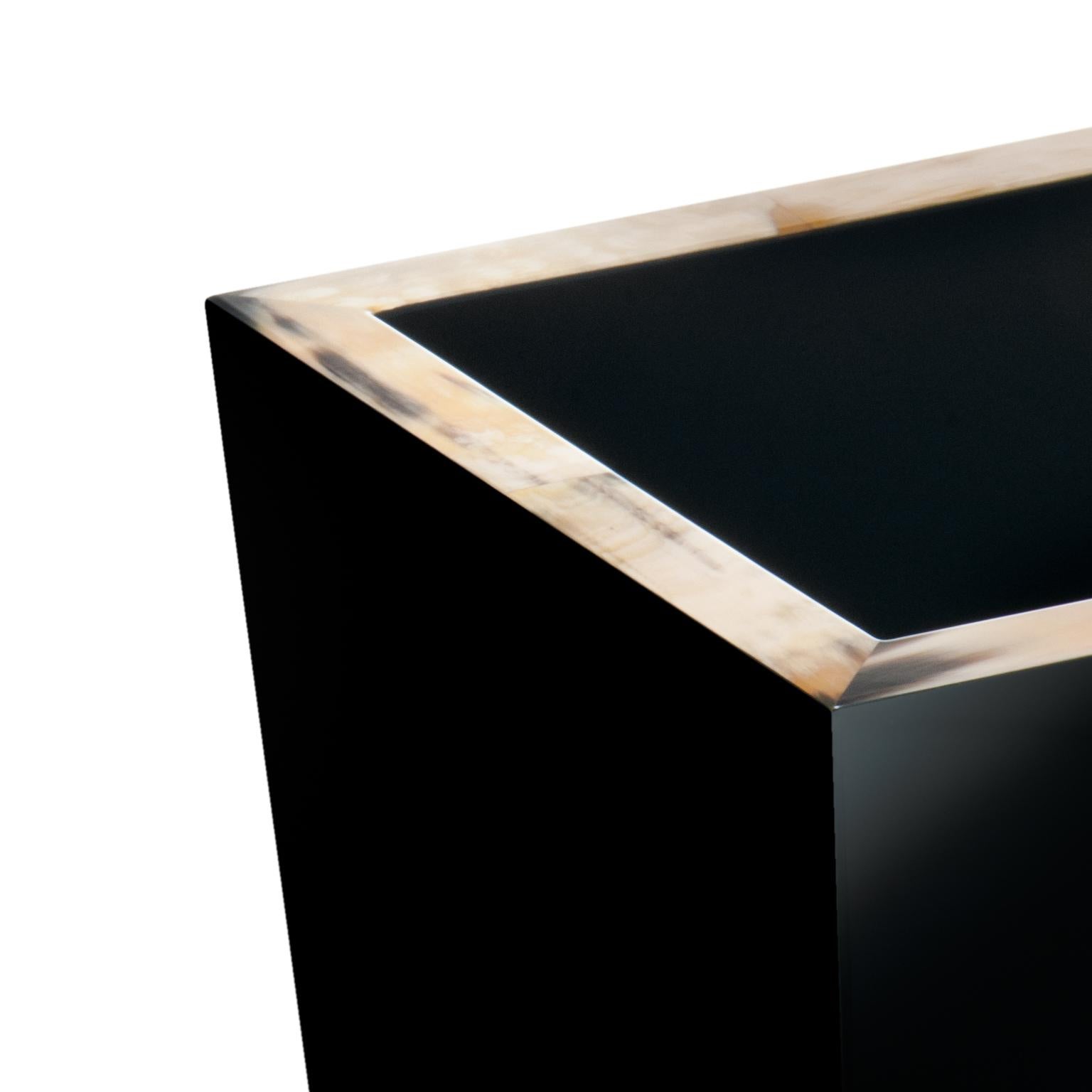 Der aus Holz handgefertigte Papierkorb Fedro hat die Form einer umgekehrten Pyramide und ist schwarz hochglanzlackiert. Dieser Papierkorb ist mit einer eleganten Umrandung aus Corno Italiano verziert und ist eine unverzichtbare Ergänzung für Ihr