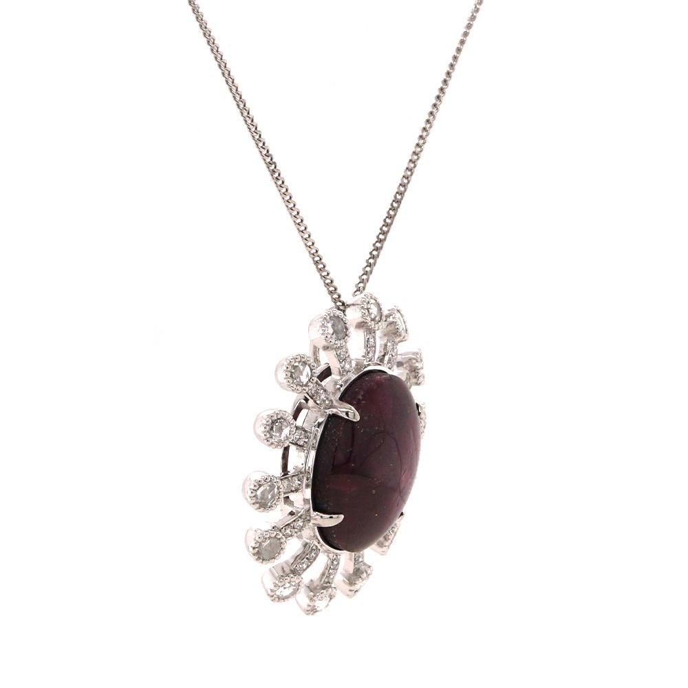 Command attention with this striking pendant, where timeless elegance meets celestial allure. At its heart lies a captivating 12.13ct star ruby, exhibiting a natural asterism that shimmers like starlight across its polished surface. Encircling this
