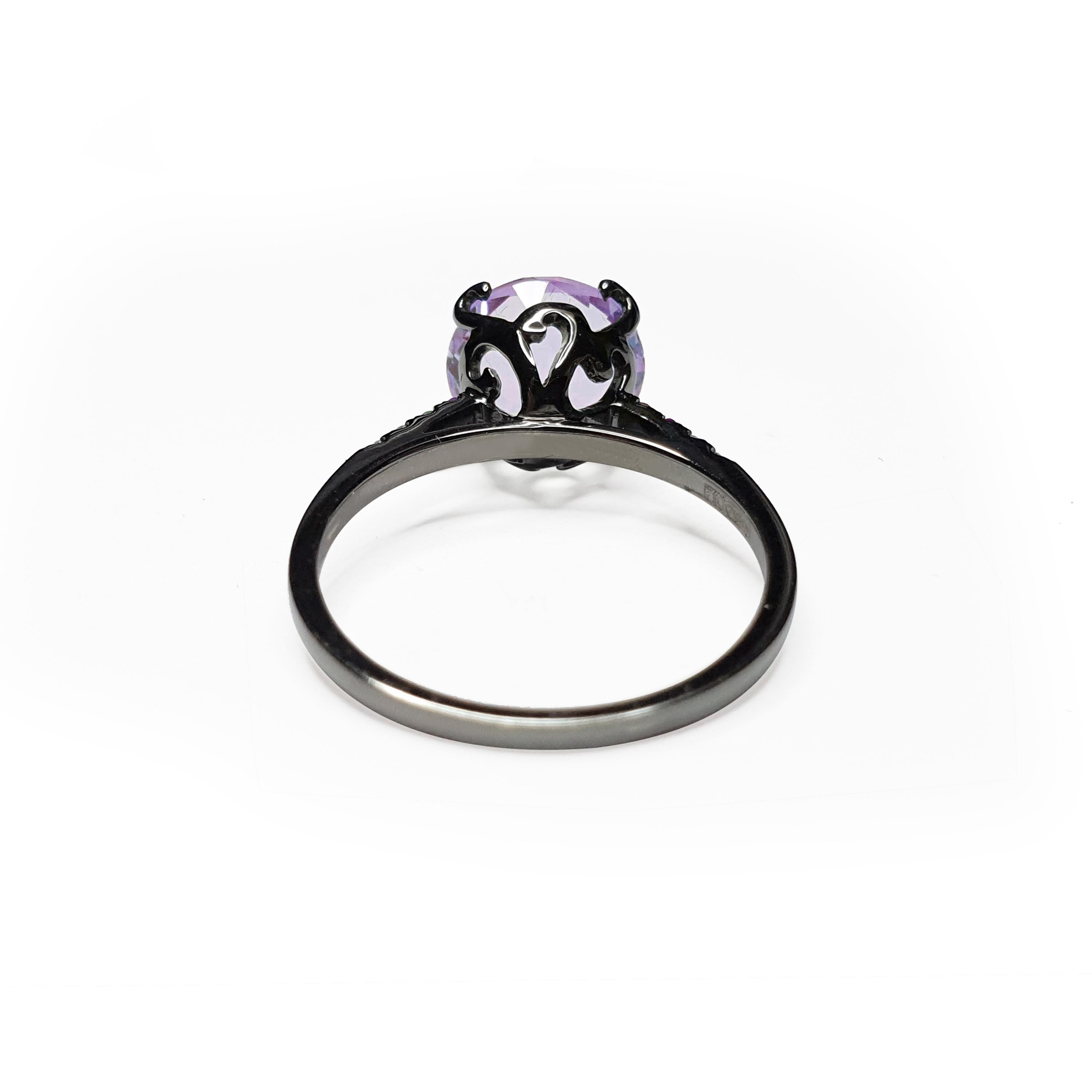 Description:
Whispering small round stone ring with a central 3ct purple amethyst and shoulder set 0.03ct white diamonds with  0.06ct purple amethysts. Set in black rhodium plate on 18ct white gold.

Available ring sizes: L (UK) / 5 3/4 (US), M (UK)
