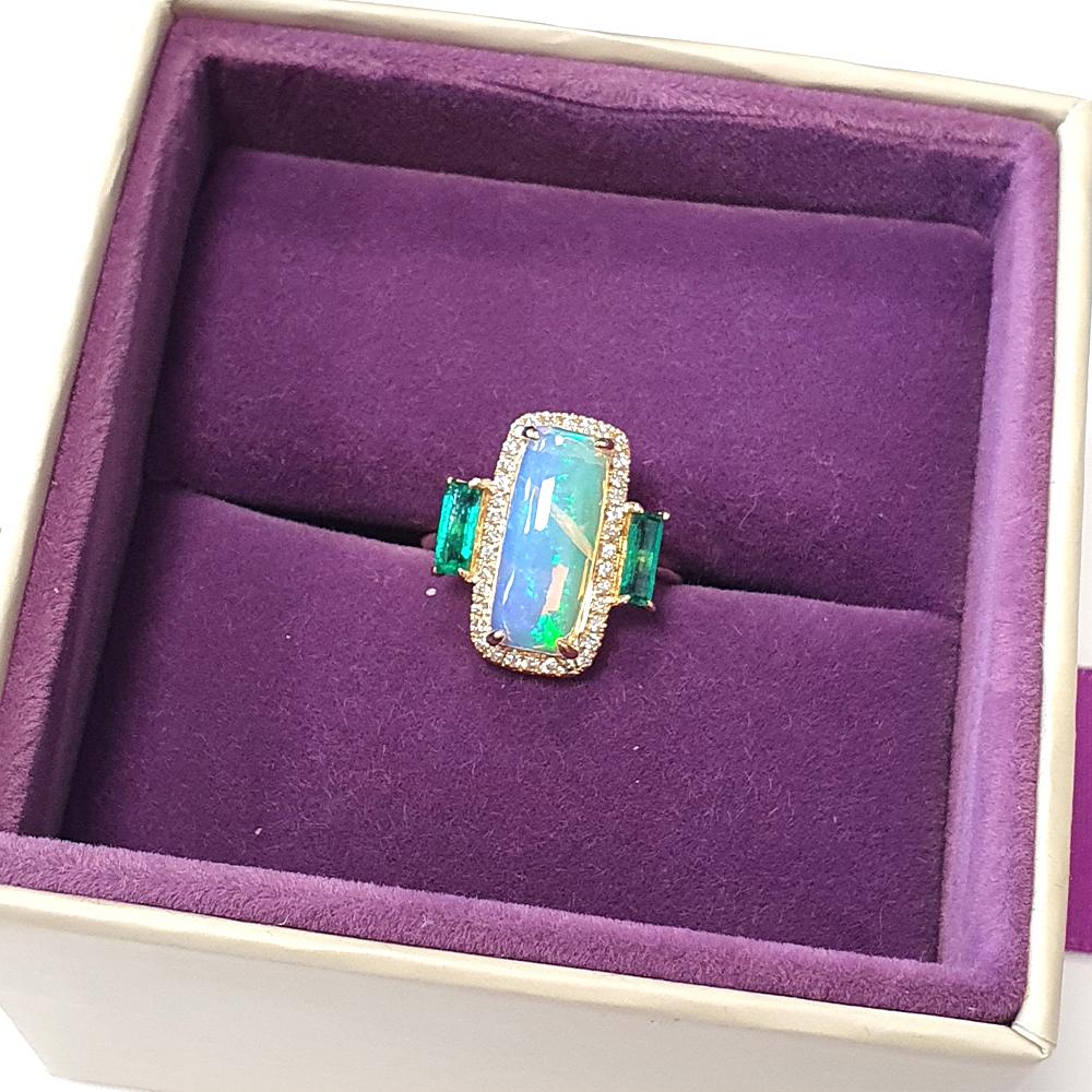 Crafted in 14ct yellow gold, this striking ring features a captivating 2.27ct rectangular opal at its centre, radiating with an iridescent play-of-colour. The opal displays a natural internal inclusion — resembling a delicate fracture — which lies