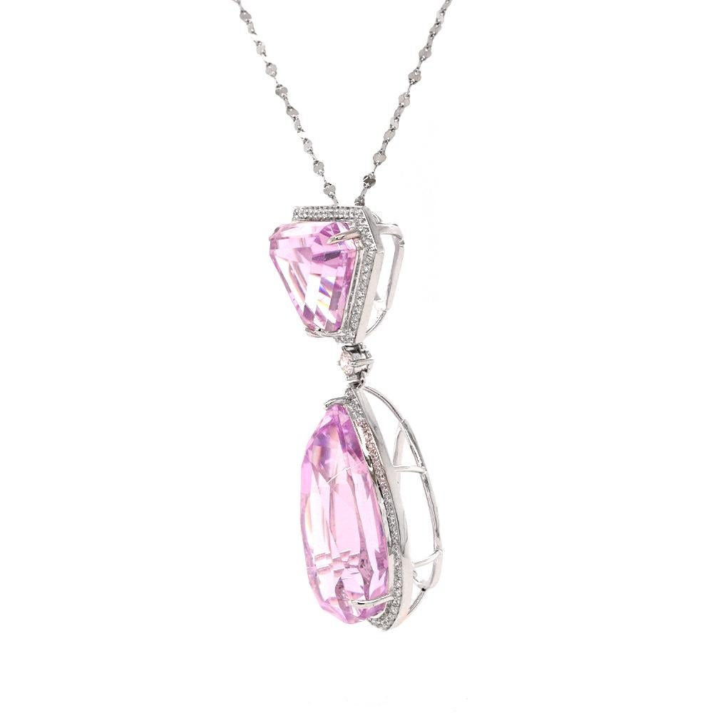 This striking pendant necklace pairs two vivid pink gemstones — a trapezoid-cut and a pear-cut — each framed by a halo of white diamonds and linked by a single brilliant-cut stone. Set in cool-toned platinum, it creates a bold yet elegant silhouette