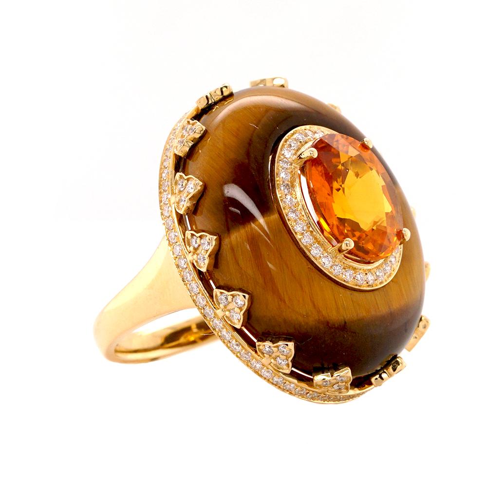 Indulge in the opulence of this 18ct yellow gold cocktail ring, a mesmerising composition of warmth, brilliance, and regal charm. It features a mesmerising 17ct tiger’s eye set within an ornate crown motif setting embellished with sparkling