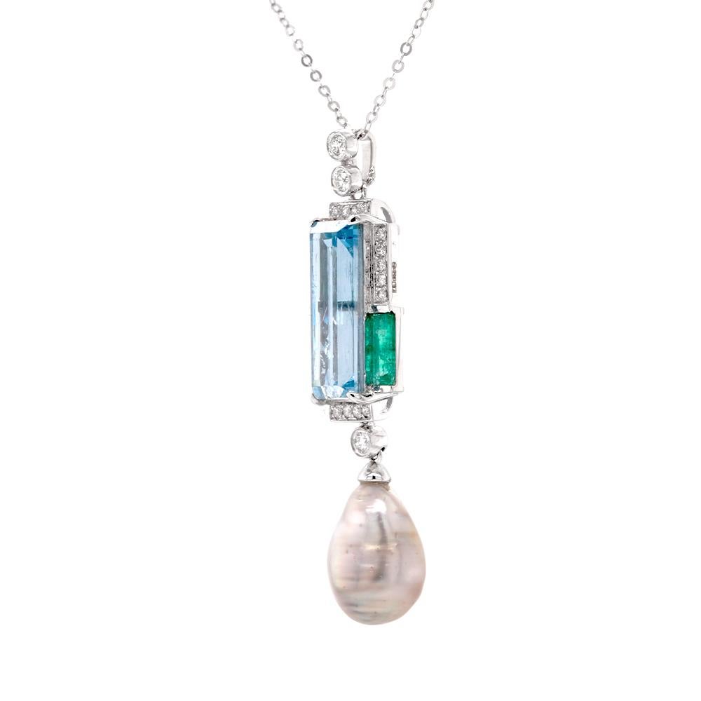 A stunning jewel in platinum – an abstract gemstone pendant showcasing a central 4.39ct rectangle-cut aquamarine, resonating with the tranquillity of ocean depths. Accompanying the aquamarine, two verdant rectangle-cut emeralds, with a total weight
