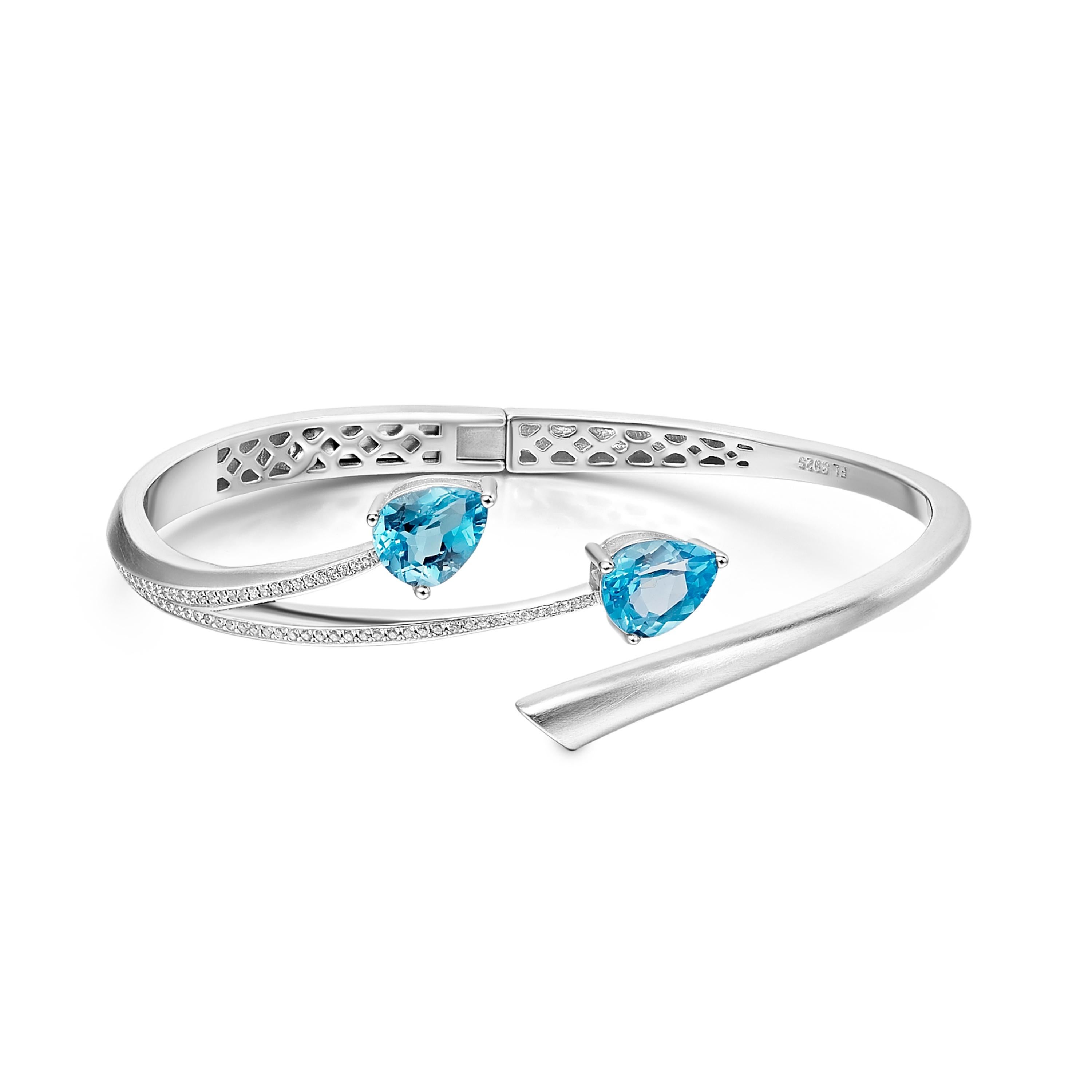 Description:
Shooting Star bangle with pear cut blue topaz and Hearts and Arrows* white cubic zirconia, set in matte polished white rhodium plate on sterling silver.

Inner diameter (LxW): small/medium = 56mm x 60 mm, large = 60mm x 65mm

*Hearts