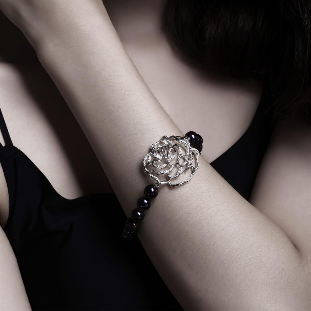 The Rose Peacock Pearl Bracelet is a captivating piece that exudes both elegance and uniqueness. Measuring 7.5 inches in length, this bracelet showcases a striking rose centrepiece, embellished with glistening gemstones that catch the light