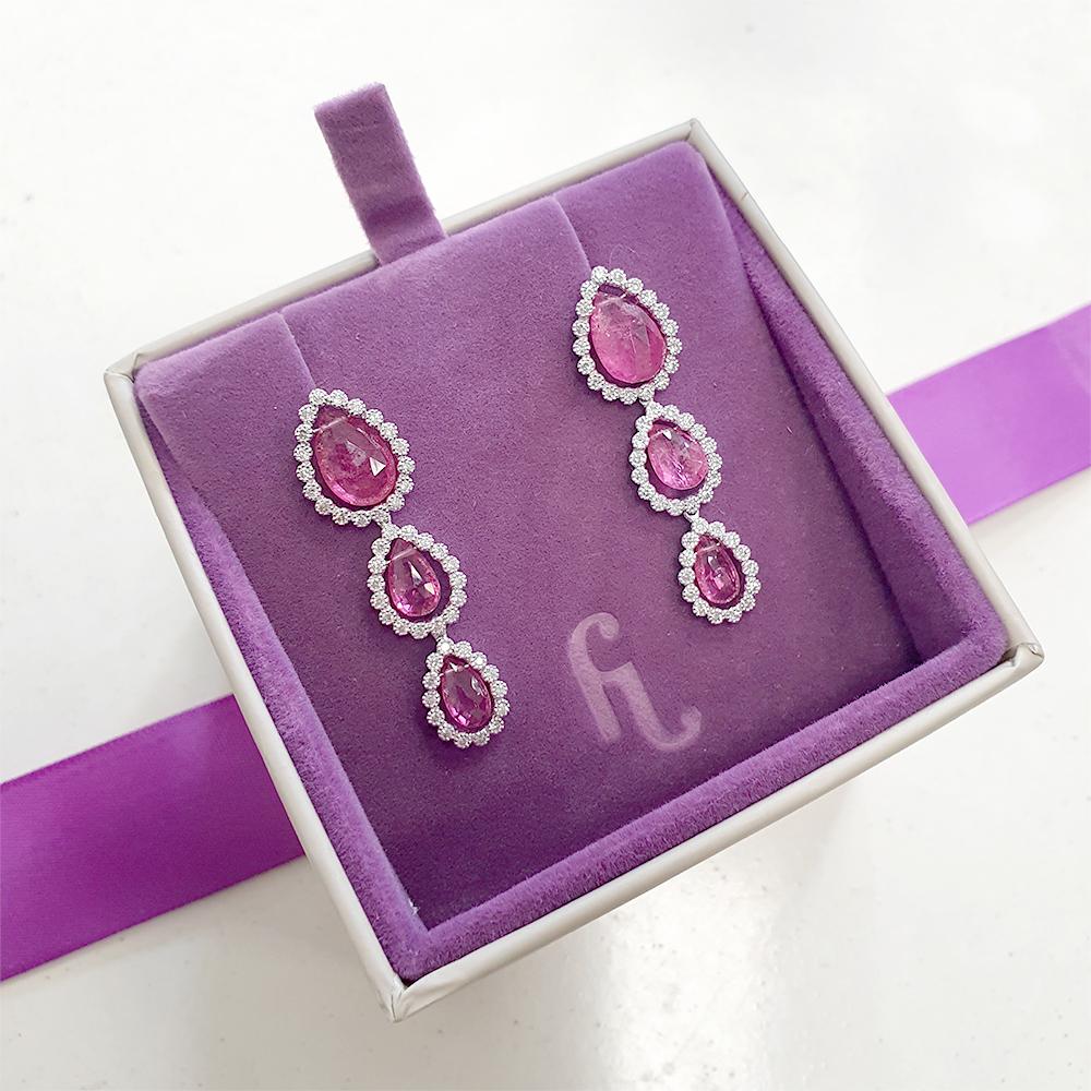 Indulge in the exquisite elegance of these graduated pink tourmaline drop earrings, expertly crafted in 18ct white gold. Each earring showcases a trio of free-hanging, pear-shaped pink tourmalines, gracefully graduated in size. These vibrant