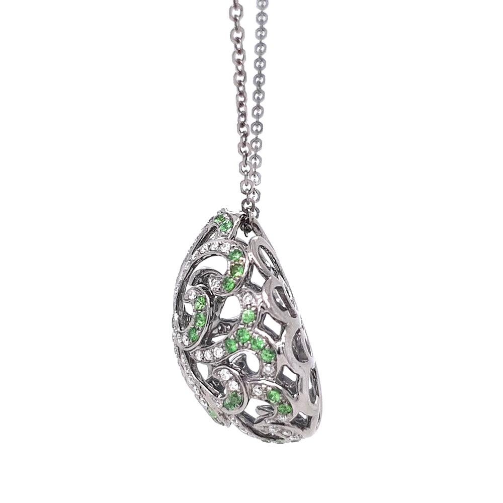 El Colgante Huevo de Filigrana Susurrante combina la elegancia atemporal con una artesanía intrincada. Engastado en oro blanco de 18 ct rodiado en negro, el diseño de huevo calado está adornado con brillantes granates verdes y diamantes