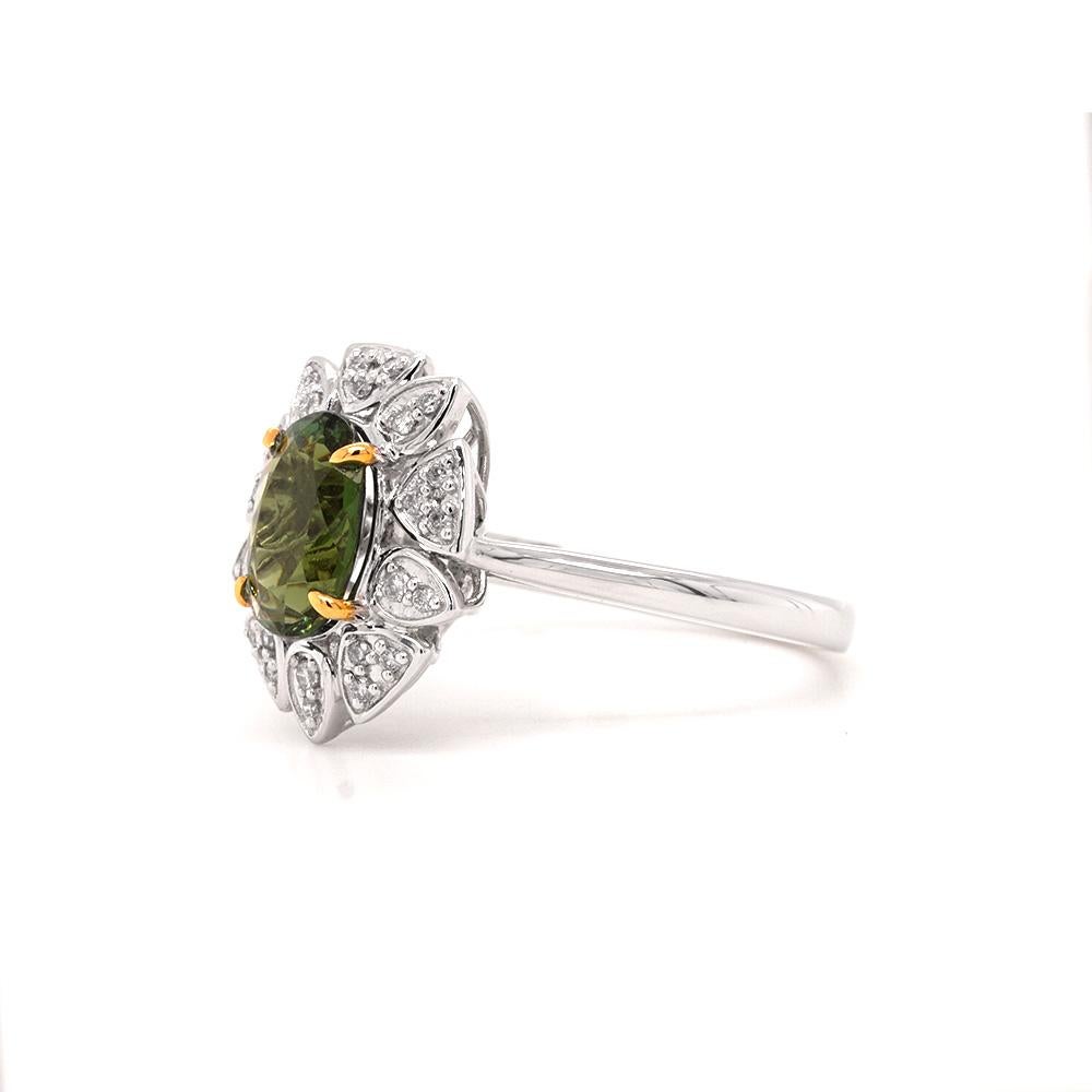 Experience the ultimate in luxury with our 18ct white gold abstract ring. Featuring a stunning green tourmaline centre stone, weighing 1.40ct. Bordered with abstract forms of 18ct gold bedazzled with diamonds, this piece is a true masterpiece of