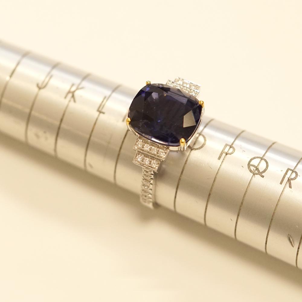 A stunning 18ct white gold ring with accents of yellow gold, designed to captivate and delight. At the heart of this exquisite piece lies a breath-taking 5.74ct iolite, boasting a rich and alluring violet-blue hue that shimmers in the light. The
