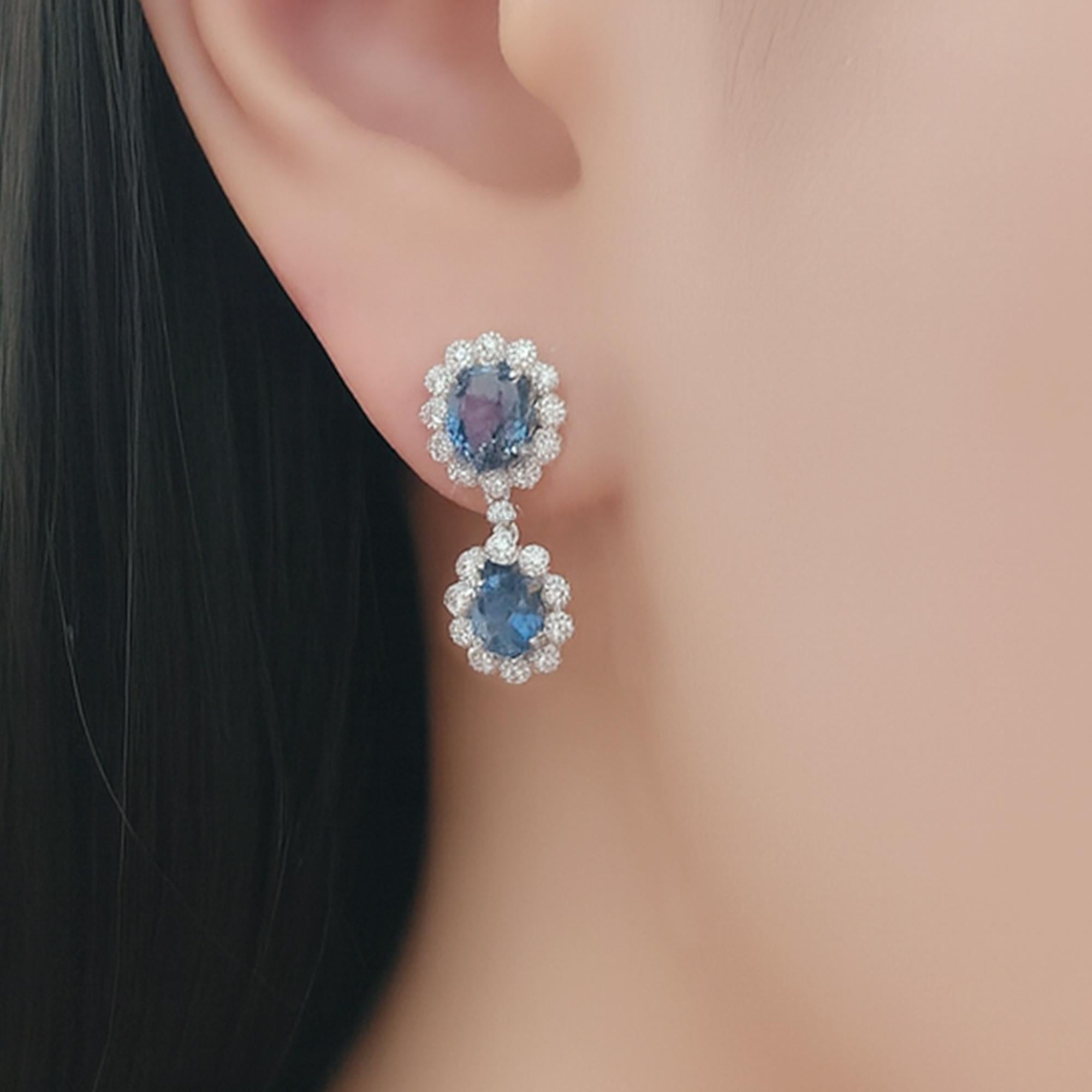 Una coppia di zaffiri abbinati - circa 3 carati in totale - scende con grazia speculare, ciascuno incorniciato da un'aureola di diamanti taglio brillante (0,30 carati) incastonati nel platino. Ogni diamante è bordato con una fine venatura, che