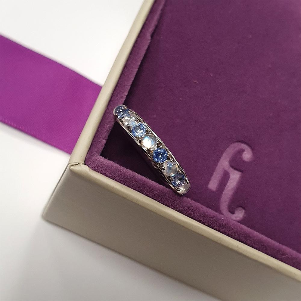 Dieser exquisite Ring aus strahlendem 18-karätigem Weißgold mit halber Ewigkeit ist eine harmonische Mischung aus himmlischem Charme und zeitloser Raffinesse. Eine faszinierende Abfolge von hellblauen Saphiren und leuchtenden Mondsteinen wechselt