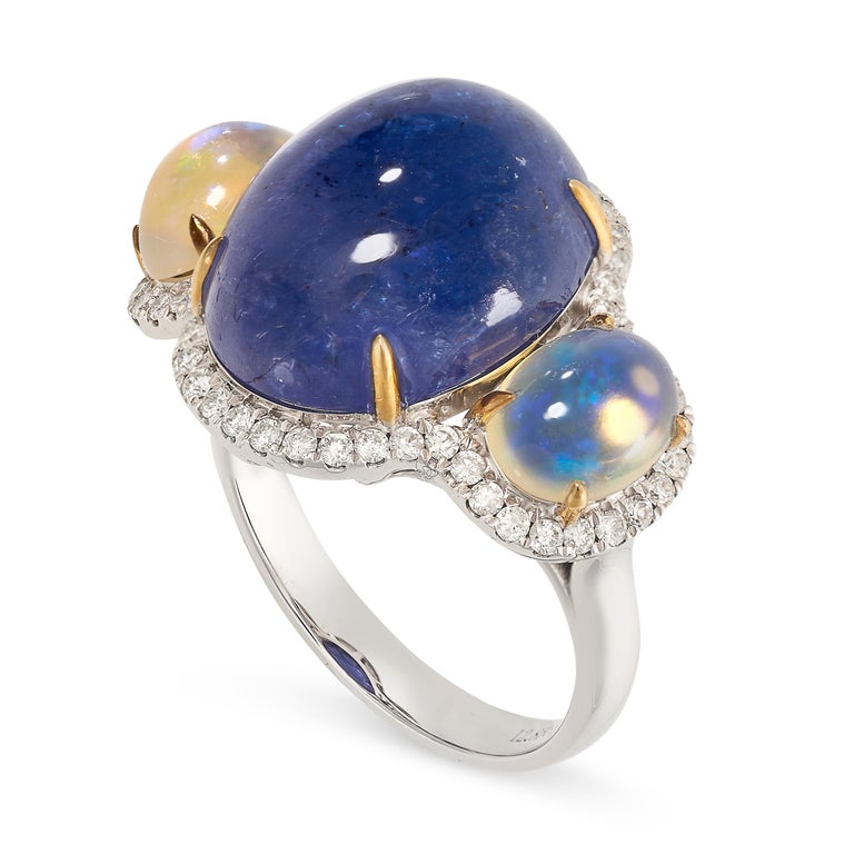 A stunning 18ct gold trilogy ring by Fei Liu, featuring three central stones of cabochon tanzanite and opals.

- Ring head dimensions (LxW): 20mm x22mm
- Weight: 8gm
- Stones: tanzanite 12.85ct, opals = 1.60ct, diamonds = 0.430ct
- Metal: 18ct white