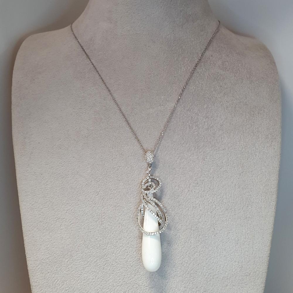 Dieser exquisite Anhänger zeigt einen atemberaubenden, tropfenförmigen weißen Achat, dessen glatte Oberfläche ein sanftes, ätherisches Leuchten ausstrahlt. Der Stein wird durch ein Band aus Sterlingsilber elegant hervorgehoben, das sich anmutig über