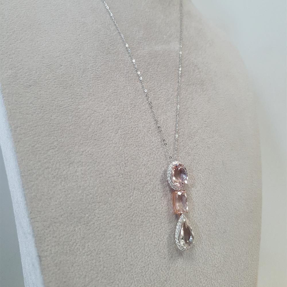 An enchanting drop pendant crafted in 18ct white and rose gold. Showcasing a harmonious blend of various cuts of morganite gems, each radiating with blush pink hues, the pendant exudes a captivating allure. Surrounding the morganites are delicate