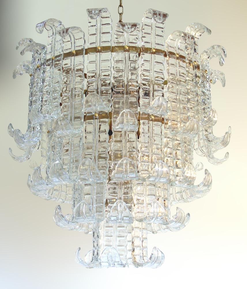 Lustre italien présenté avec quatre niveaux de verres de fougère Murano transparents soufflés à la main et montés sur une monture en métal au fini bronzé / Fabriqué en Italie 
Diamètre : 31,5 pouces / Hauteur : 27,5 pouces plus la chaîne et le