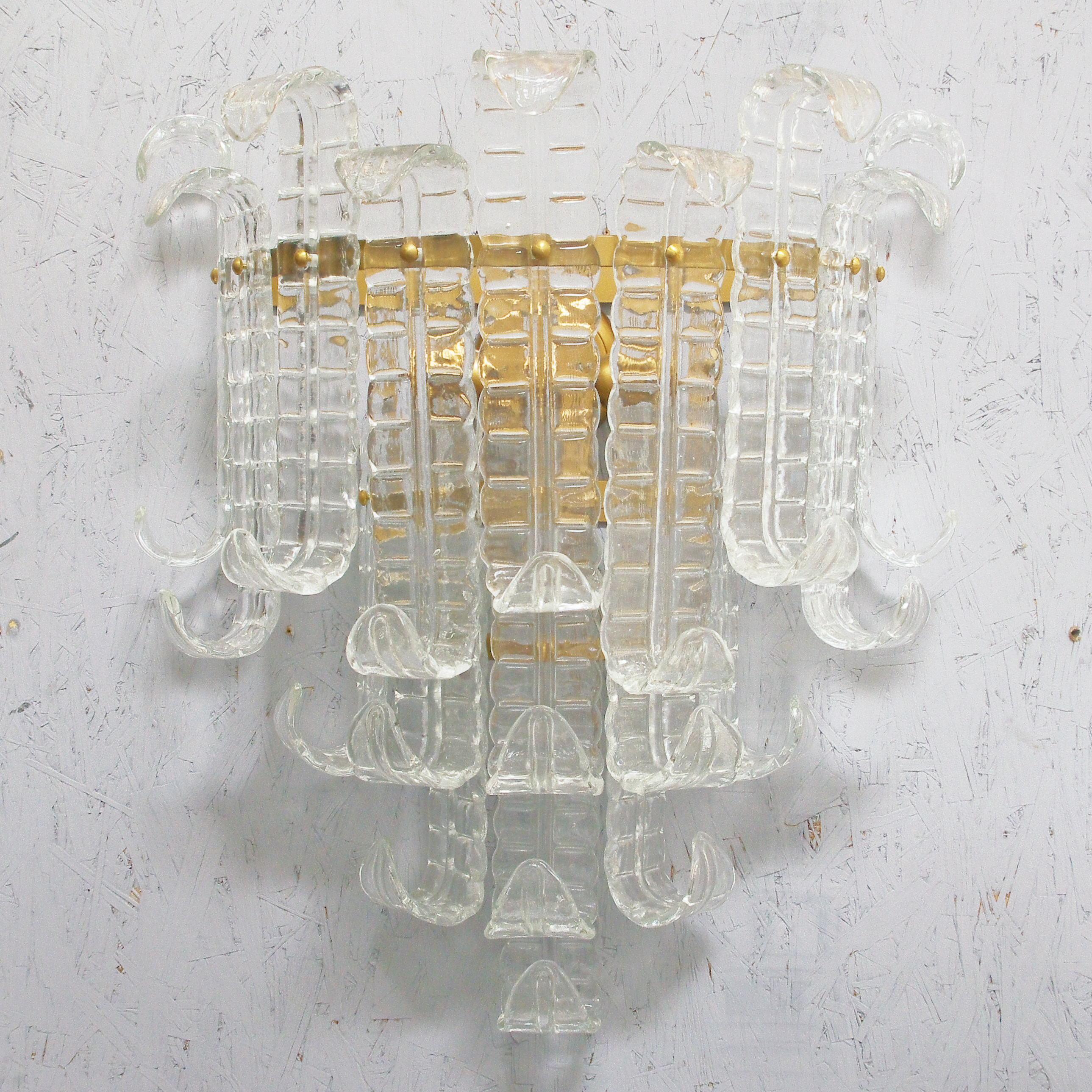 Aplique italiano con cristales transparentes soplados a mano de helecho de Murano Felci, montado en una estructura metálica con acabado bronceado, por Fabio Ltd / Made in Italy
3 luces / tipo E12 o E14 / máx. 40W cada una
Medidas: Alto 27,5