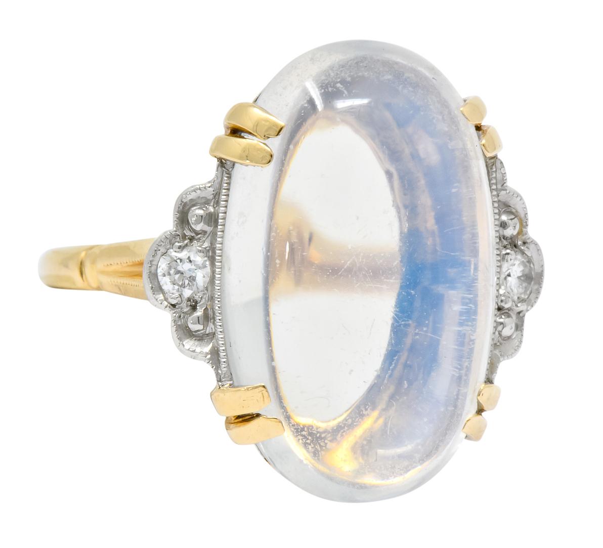 Centering an oval cut cabochon moonstone measuring approximately 7/8 x 9/16 inch, transparent with slight blue adularescence

Flanked by platinum scallop detail with millegrain, bead set with round brilliant cut diamonds weighing approximately 0.10