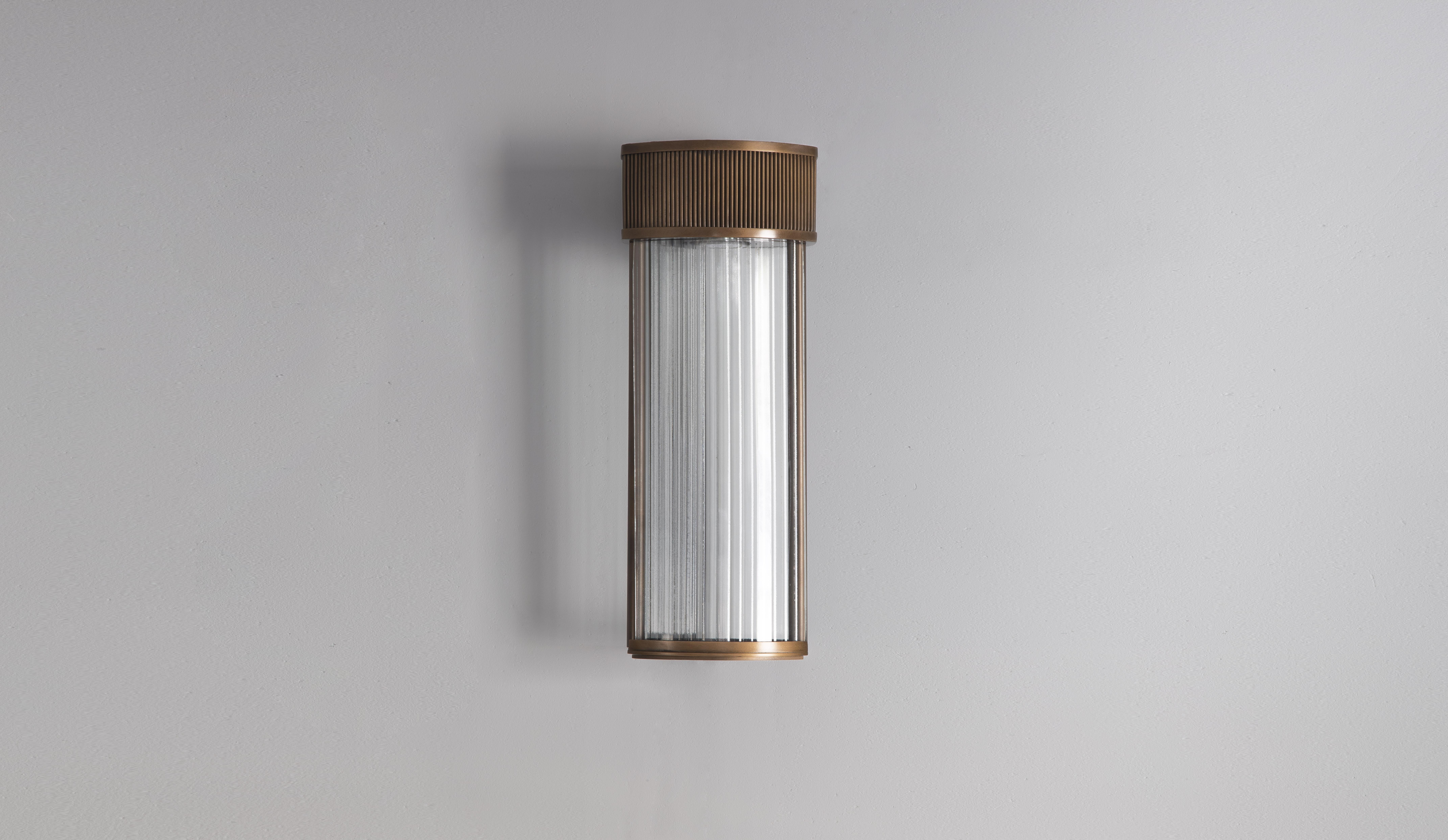 This sophisticated yet minimal Art Deco style wall light is a beautiful combination of bronzed brass and riffled glass. Modern yet timeless. Distinctive in its style and use of clean geometric forms. Inspired by architecture. This lighting fixture