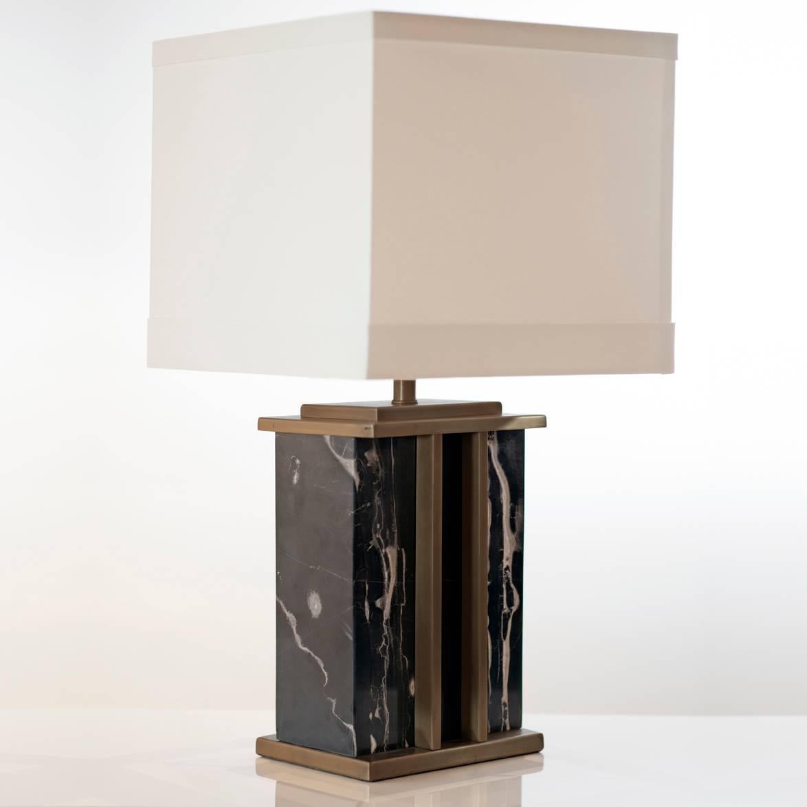 Elegant brass and marble decorative table lamp. The structure of the lamp is made from a black marble with grey veins, the lamp is then finished with brass plinths and brass detailing running vertically down the body of the lamp. This robust lamp