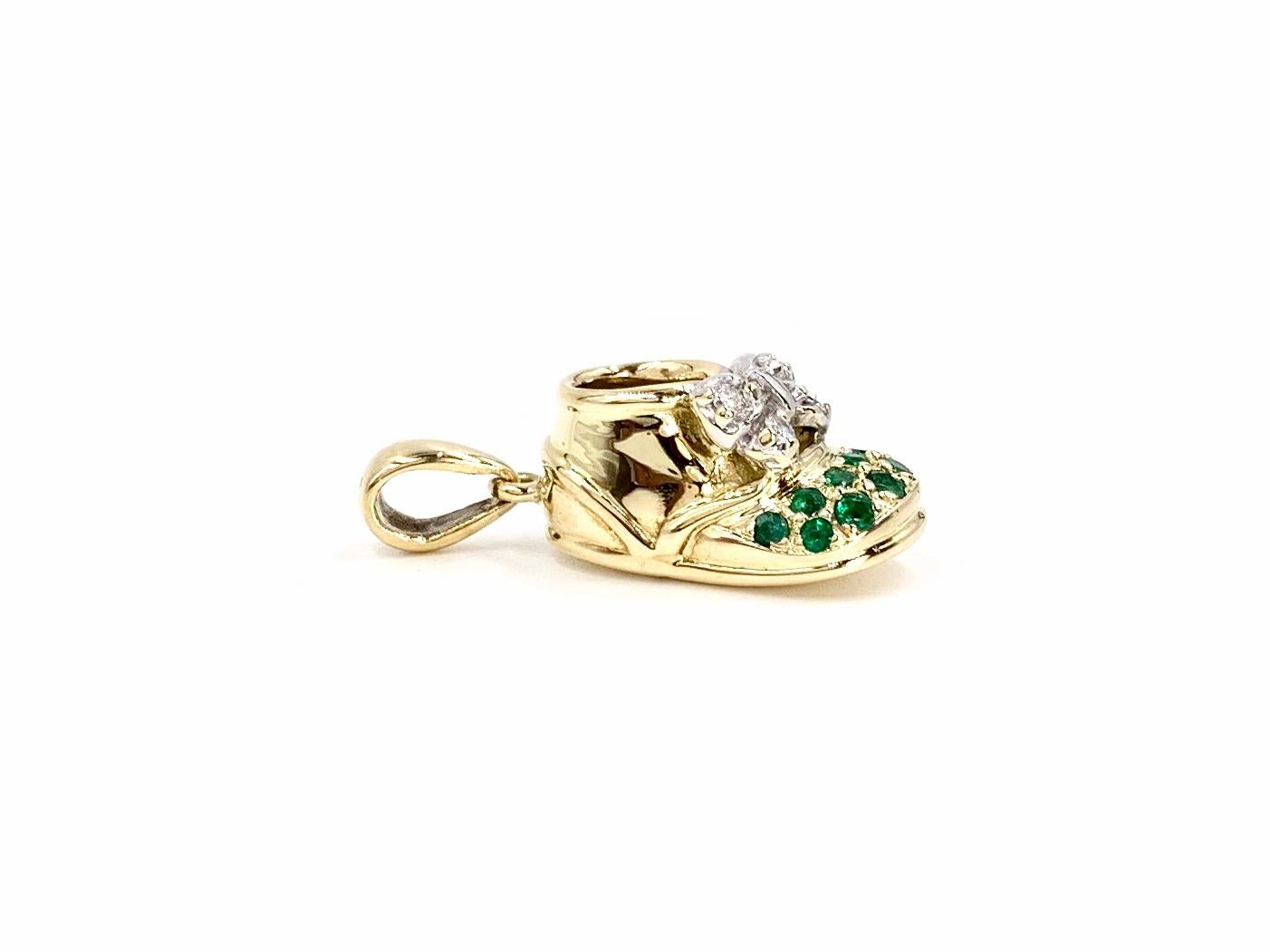 Authentic Felix B. Vollman & Co. solid 18 karat yellow gold baby shoe pendant/charm adorned with emeralds on the toe and diamonds on the white gold bow. Emeralds have an approximate total weight of .40 carats with excellent saturation. Diamond