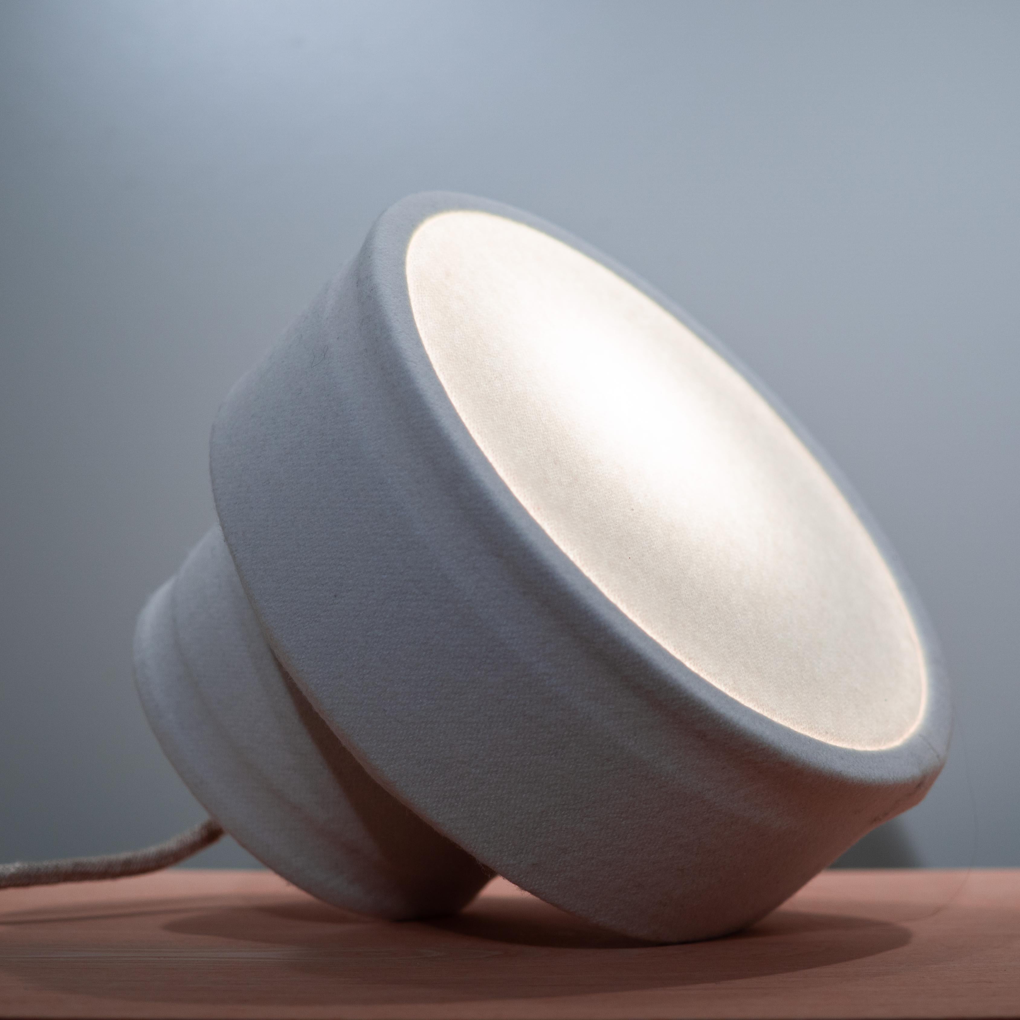 Felto is a handcrafted, minimalistic luminaire, purposed to be used as a decorative table or bedside lamp. The light is subtly diffused throughout Felto's eccentric form, adding a calming warmth in the ambience.

Three colors are available: white/