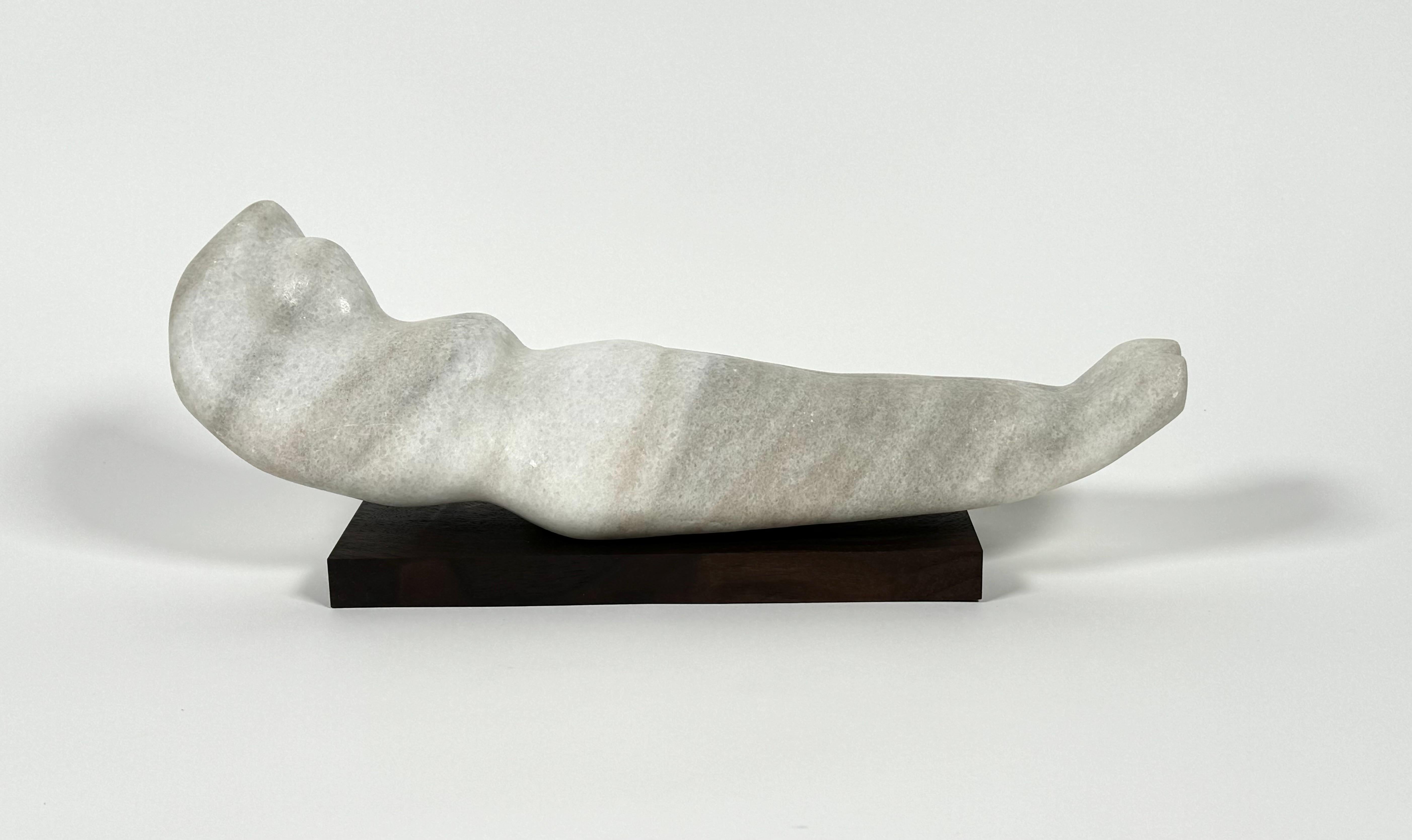 Abstract figurative sculpture in marble on a walnut base, a naive study of the female form, possibly a student of art work. The reclining form resting on a black walnut plinth base, the marble has some light graining of gray against the off white.