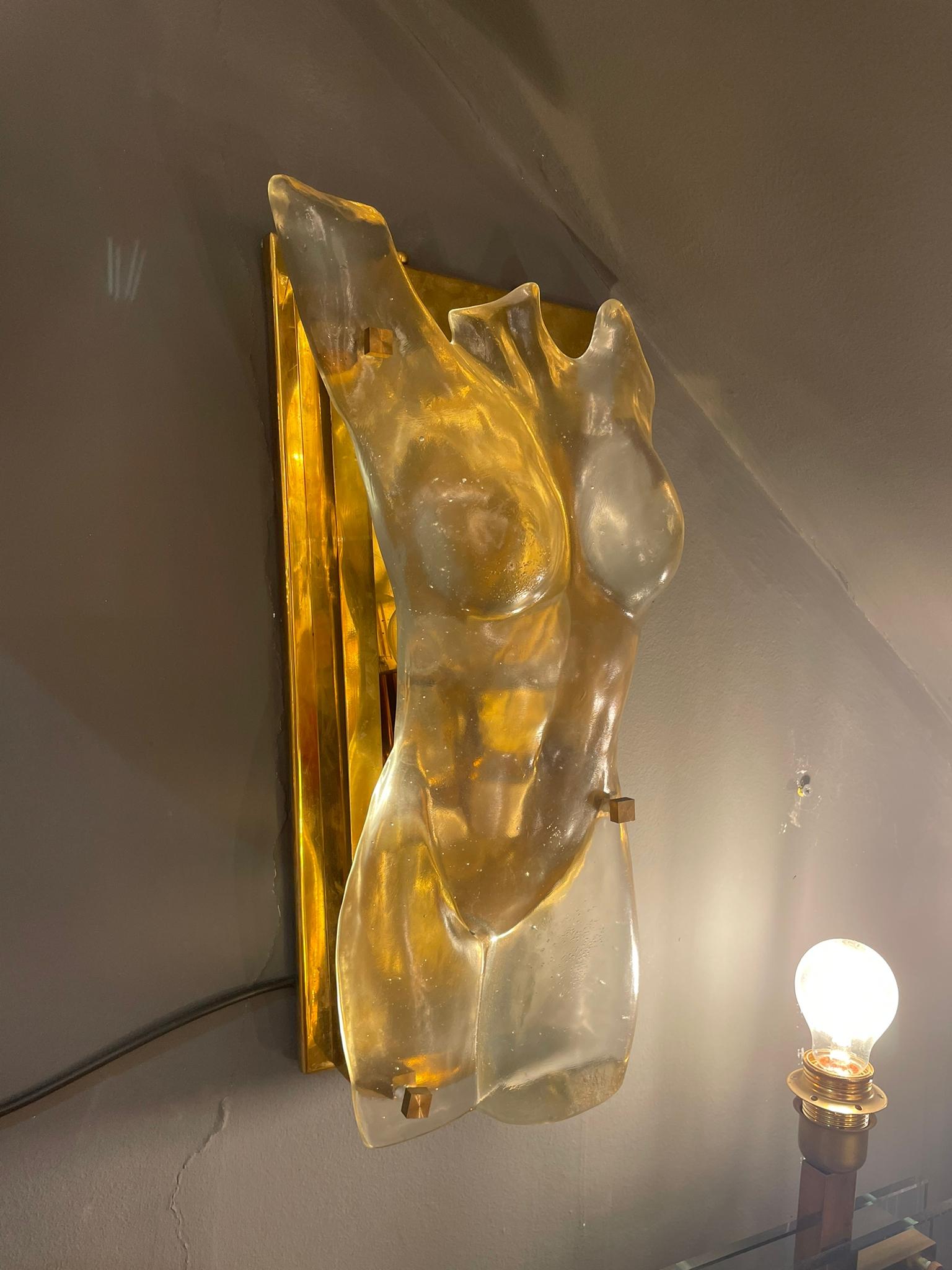 An elegant sculptural wall lamp in glass in the shape of female bust, mounted on a brass fixture. Italy, circa 1980s.
 