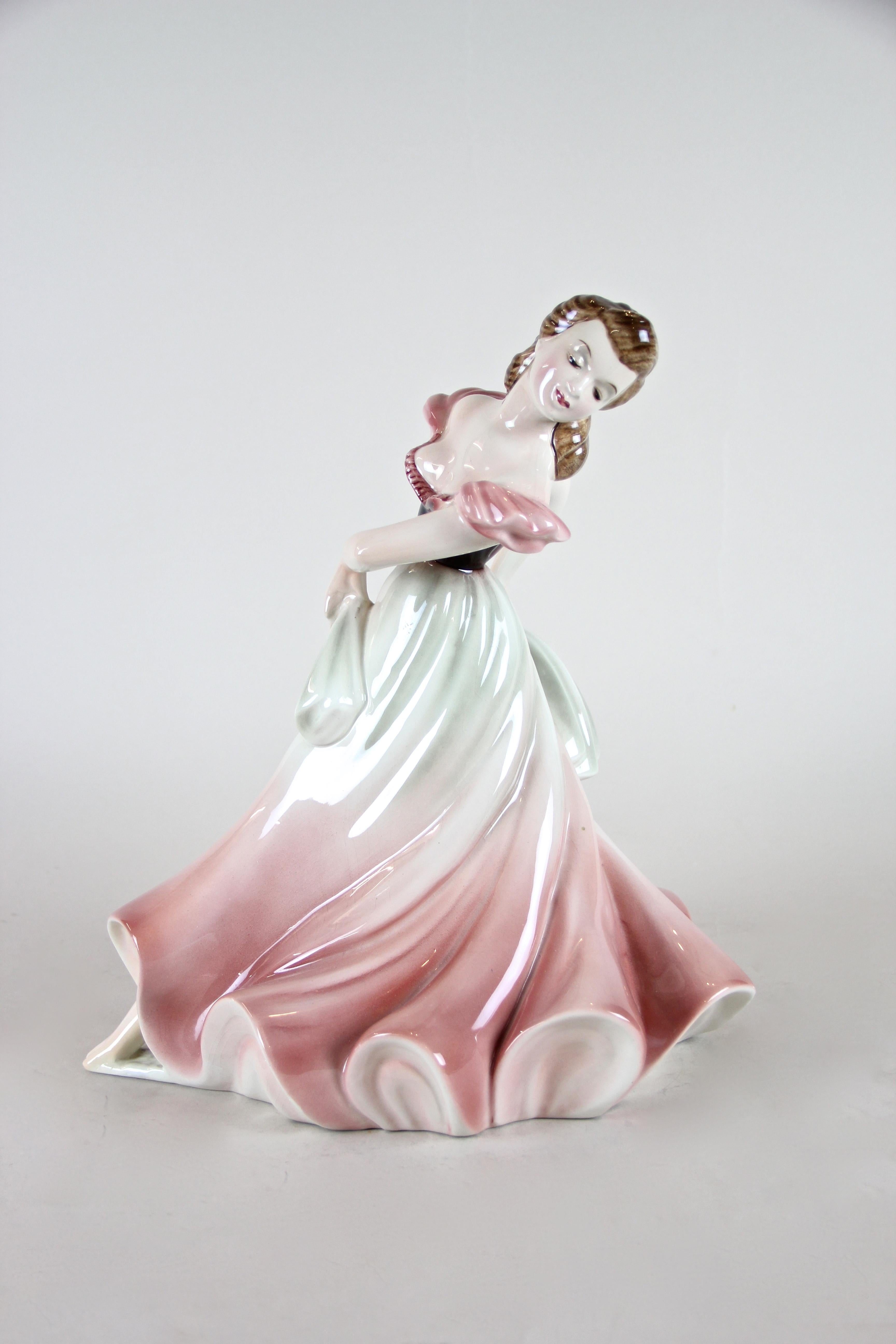 Lovely female dancer sculpture made by Keramos Vienna, Austria, circa 1925. The charming ceramic sculpture depicts a pretty lady/ dancer in a wonderful wide pink and grey dress. This Art Deco sculpture was designed by famous Stephan Dakon and comes