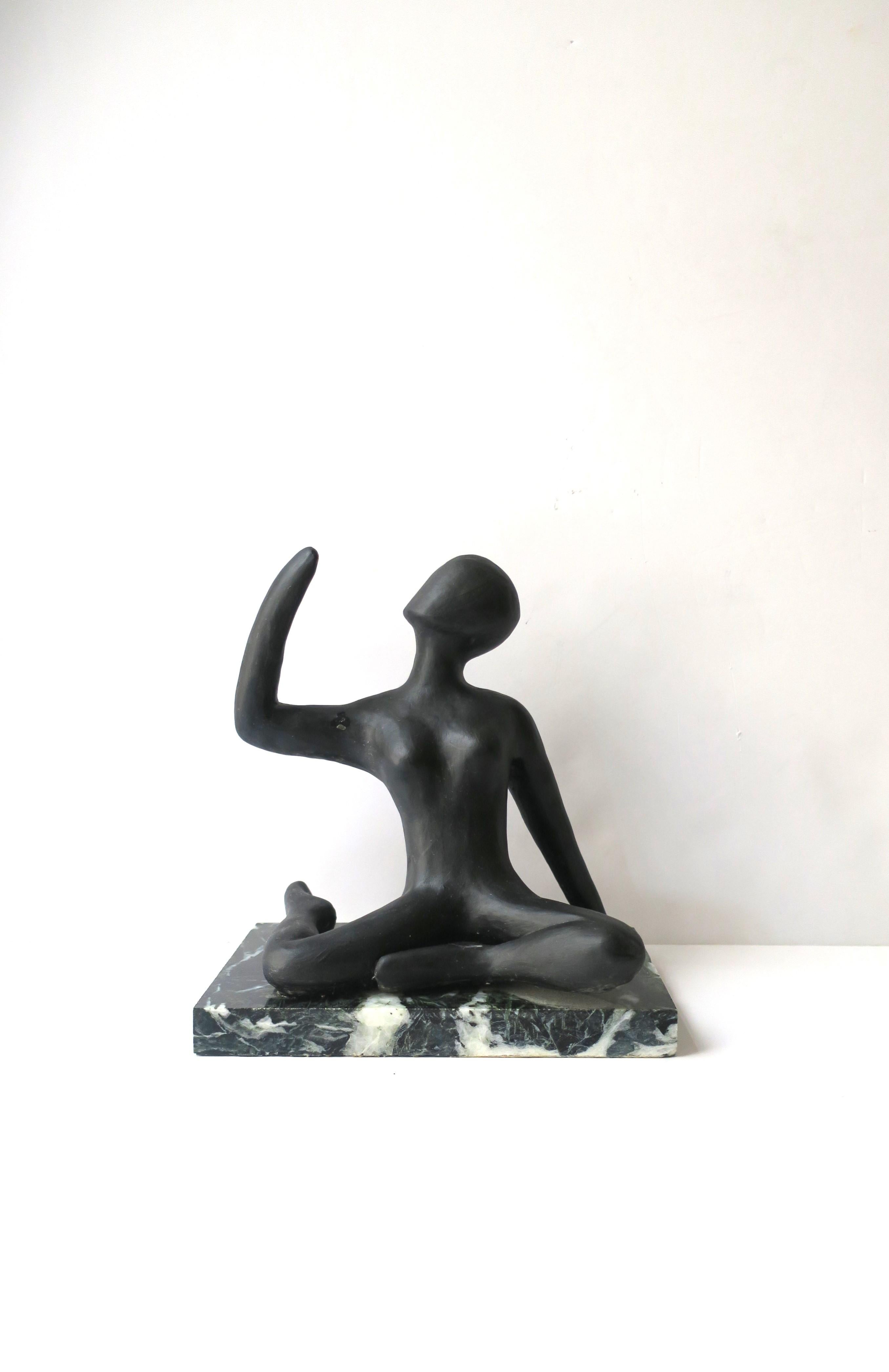 A substantial ceramic female figurative sculpture on marble base, circa mid-20th century. Female figure is ceramic with a black finish, sitting in flexible position, on a dark green and white marble base. A great piece for a bookshelf, on top of