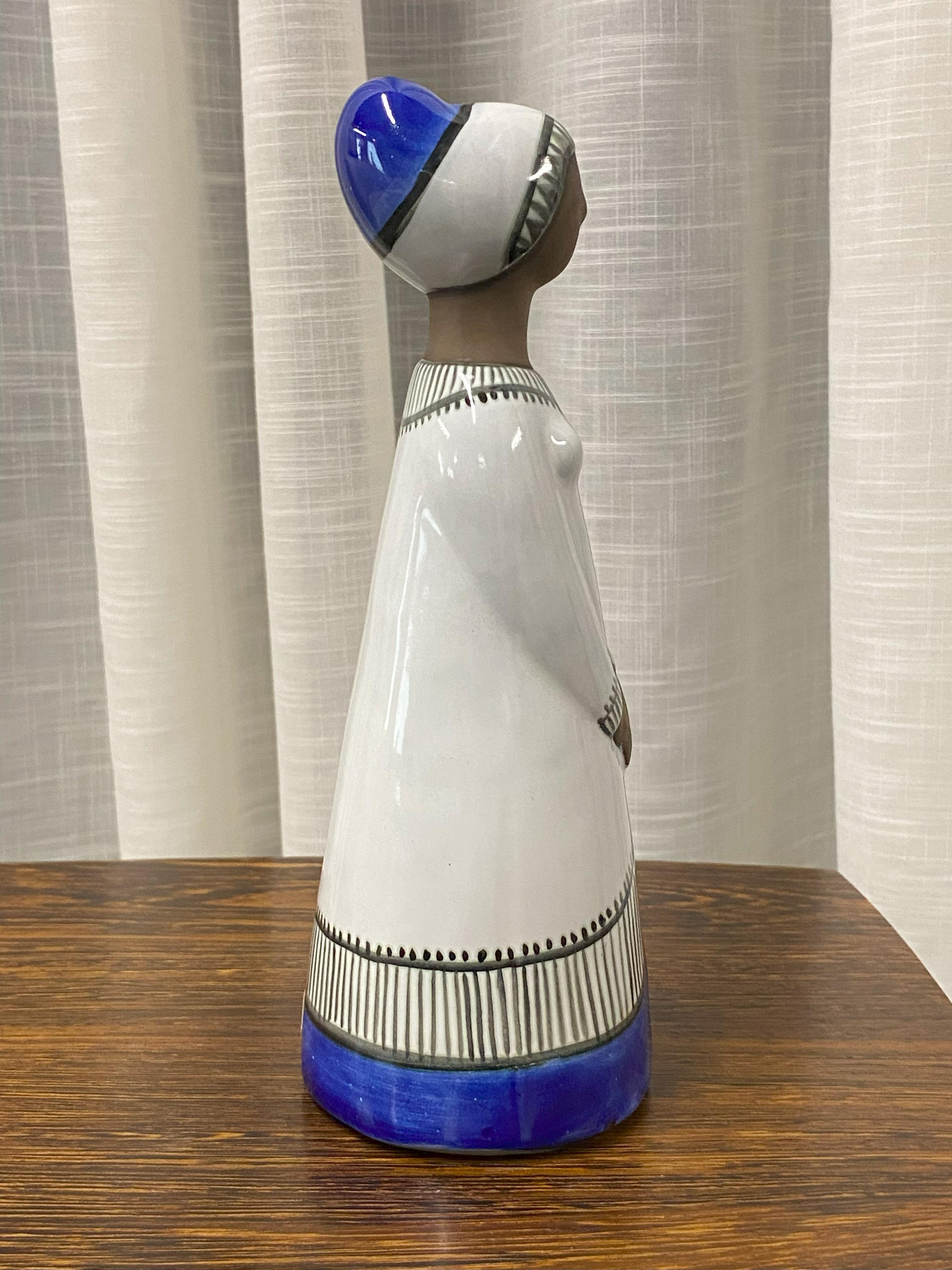 Mari Simmulson (1911-2000) für Upsala-Ekeby, Schweden. Große Keramikfigur einer Frau. Handdekoriert mit Weiß, Schwarz und Kobaltblau (Hände und Gesicht unglasiert). 

Modell 9032M. Ungefähr 1960. Markiert. Sehr guter Zustand.  Mari Simmulson gilt
