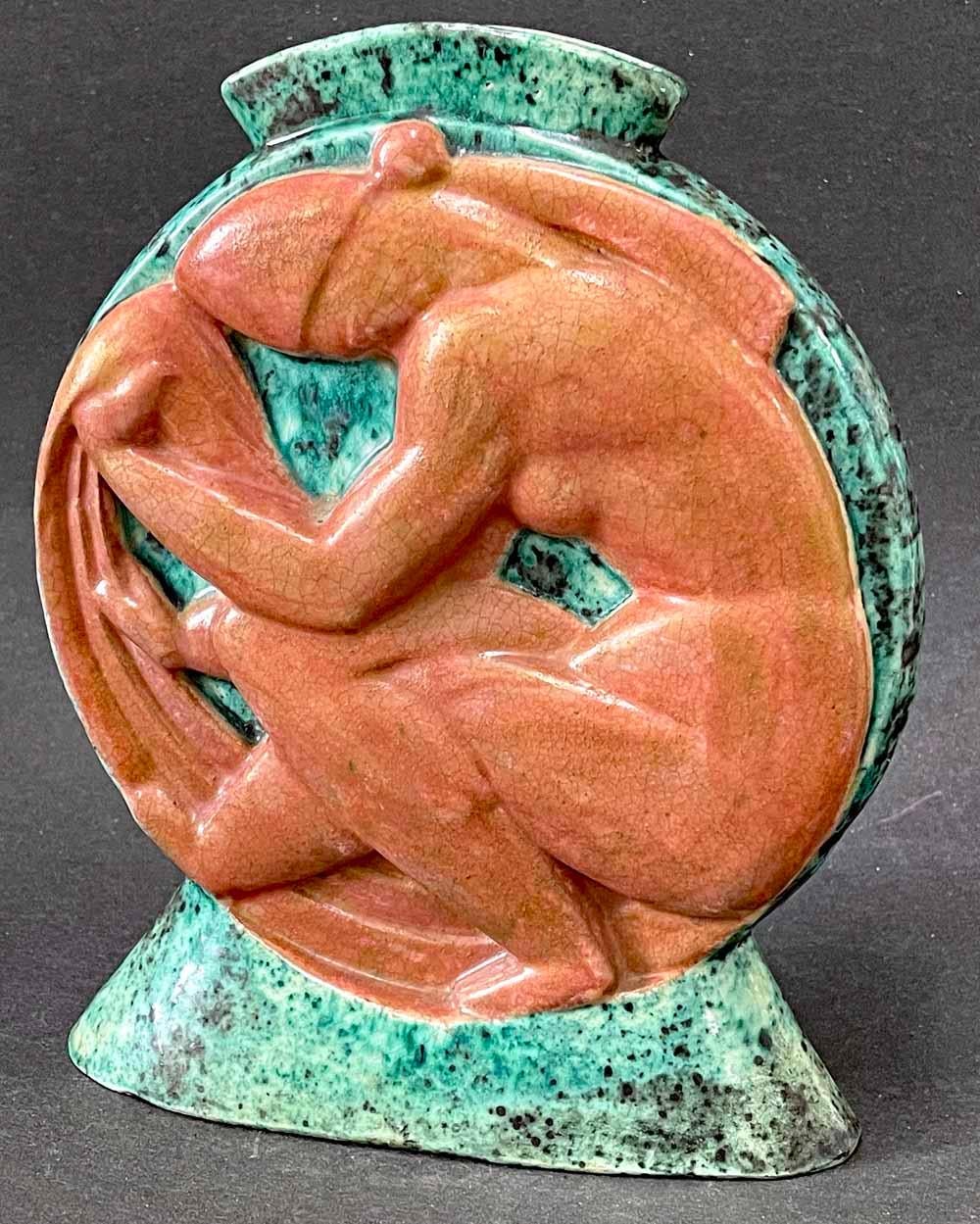 Boldly sculpted and glazed by one of the masters of French Art Deco, this vase is dominated by a seated female nude figure, her scarfed head bowed and her legs crossed, glazed in a rich terra cotta hue, in strong bas relief.  The surround is a