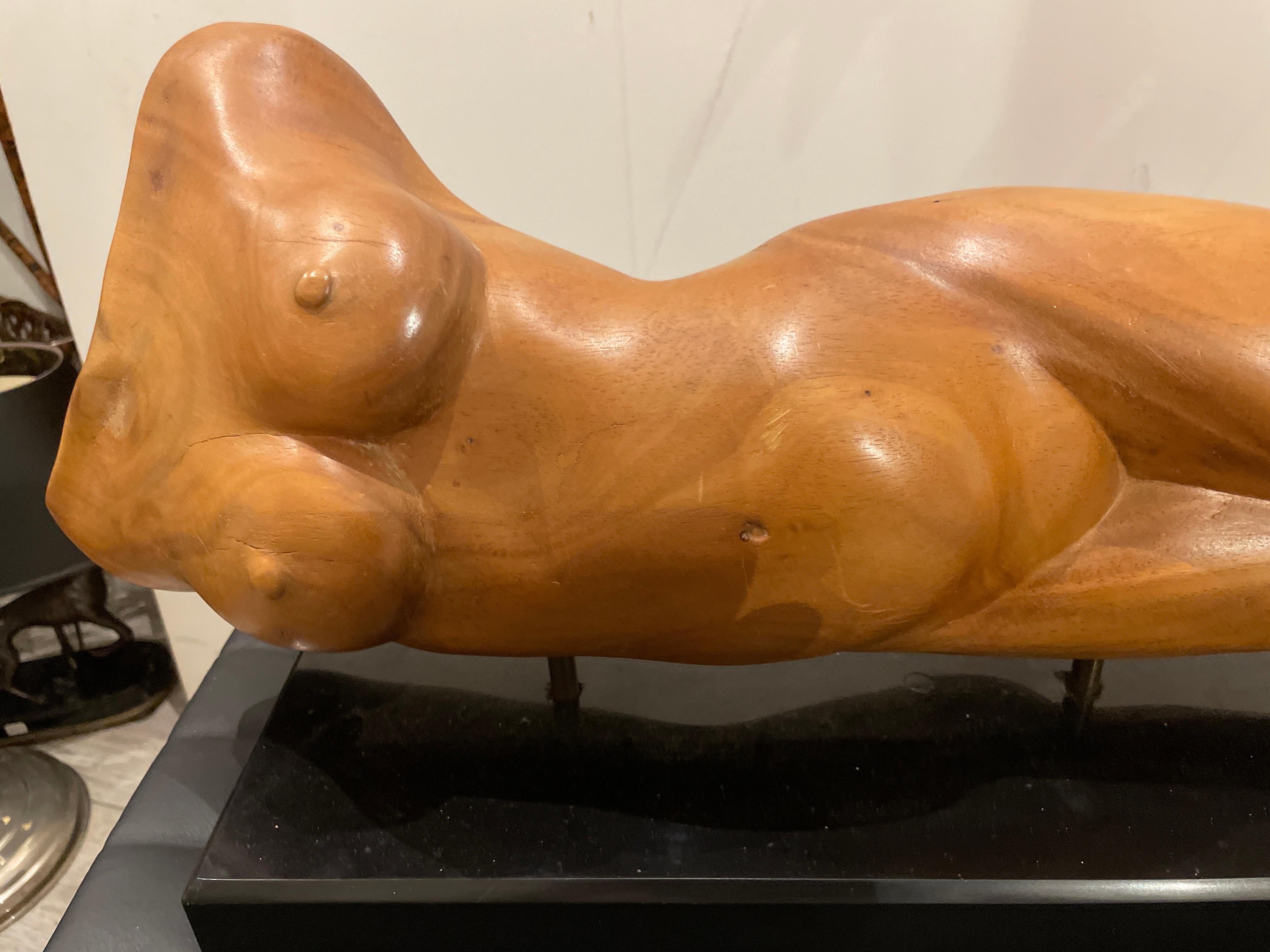 Mid Century Modern female nude sculpture done in wood set on a black marble base.