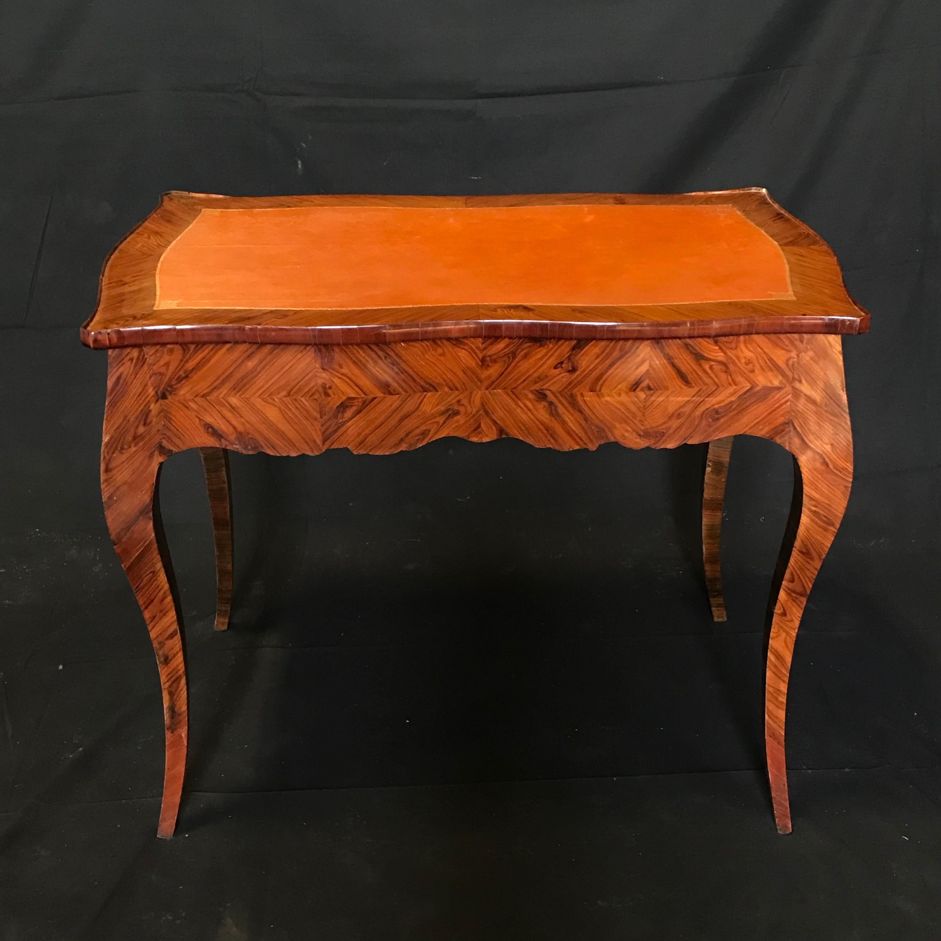 An elegant French Louis XV style petit writing desk having gilt bronze escutcheon, one central locking drawer and an immaculate original embossed brown leather writing surface, all with beautiful bois de rose marquetry. #4595
Measures: H skirt