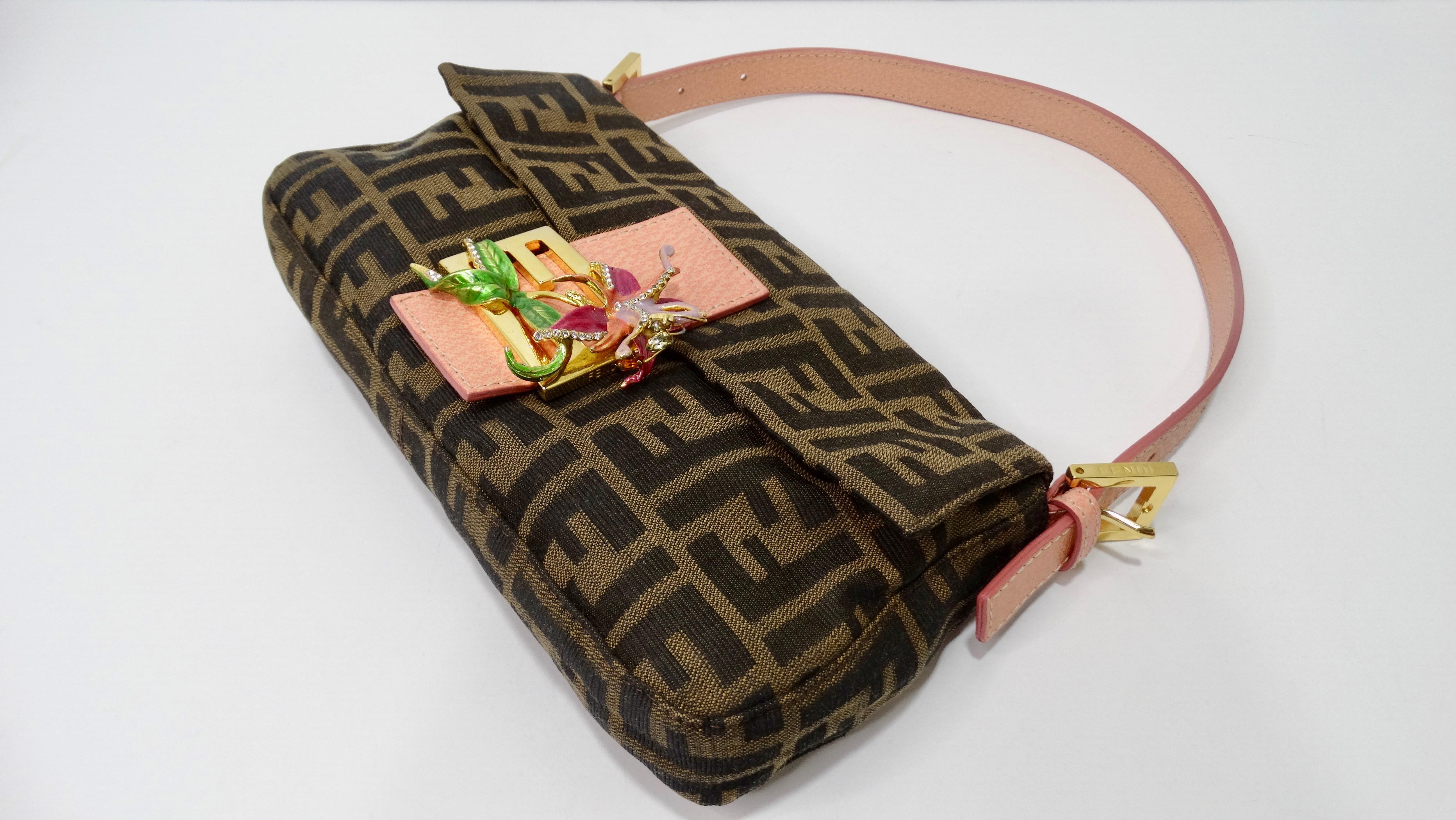 Everyone needs a Fendi baguette in their closet! Circa 1990s, this baguette features the iconic Zucca print on canvas, pink leather flat top handle, and on the front is a gold-tone Fendi logo buckle adorned with a rhinestoned metal flower. Interior