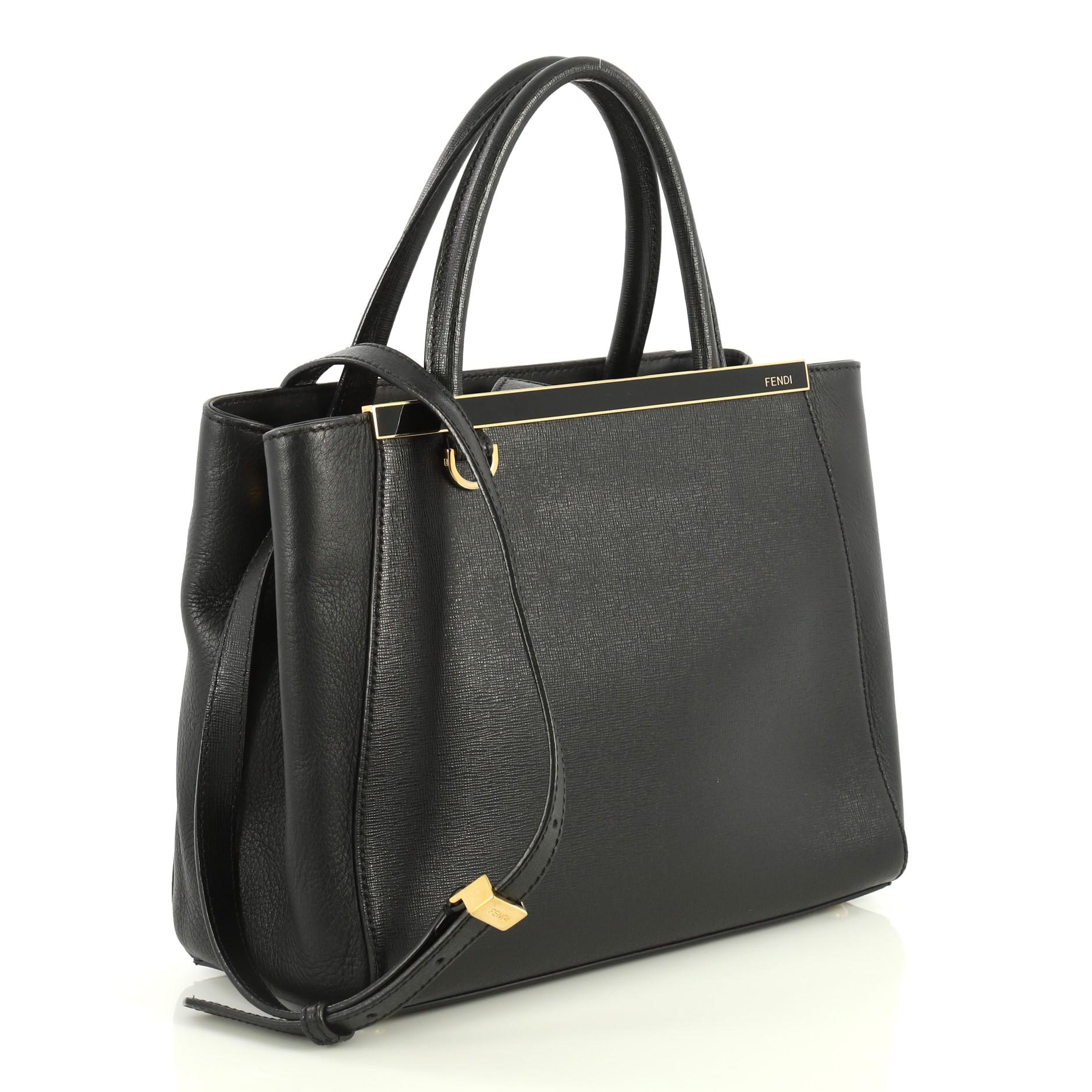 This Fendi 2Jours Bag Leather Petite, crafted from black leather, features dual rolled leather handles, top bar with Fendi brand name, and gold-tone hardware. Its top snap tab closure opens to a black fabric interior with a middle zip compartment.