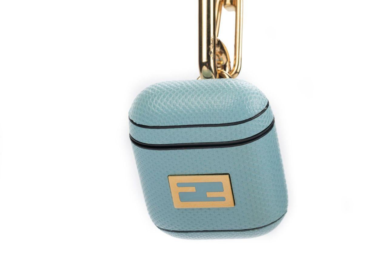 Fendi charm crafted of leather in light blue with a gold clasp. The charm can be used as an AirPod case. The piece is brand new and comes with a box.